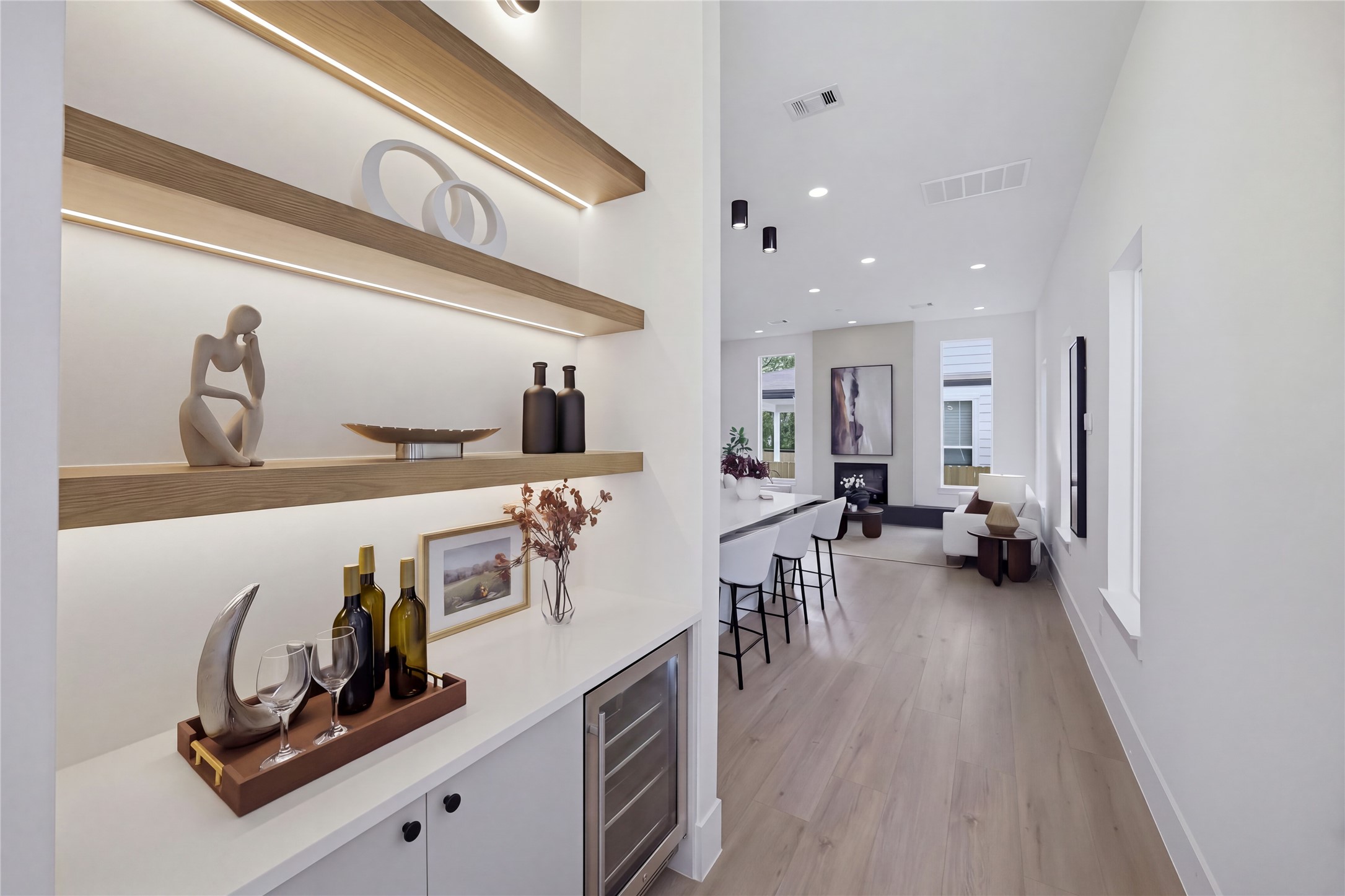 Sleek and modern hallway leading to an open-concept living area, featuring stylish built-in shelving and a wine fridge Sleek and modern hallway leading to an open-concept living area, featuring stylish built-in shelving and a wine fridge