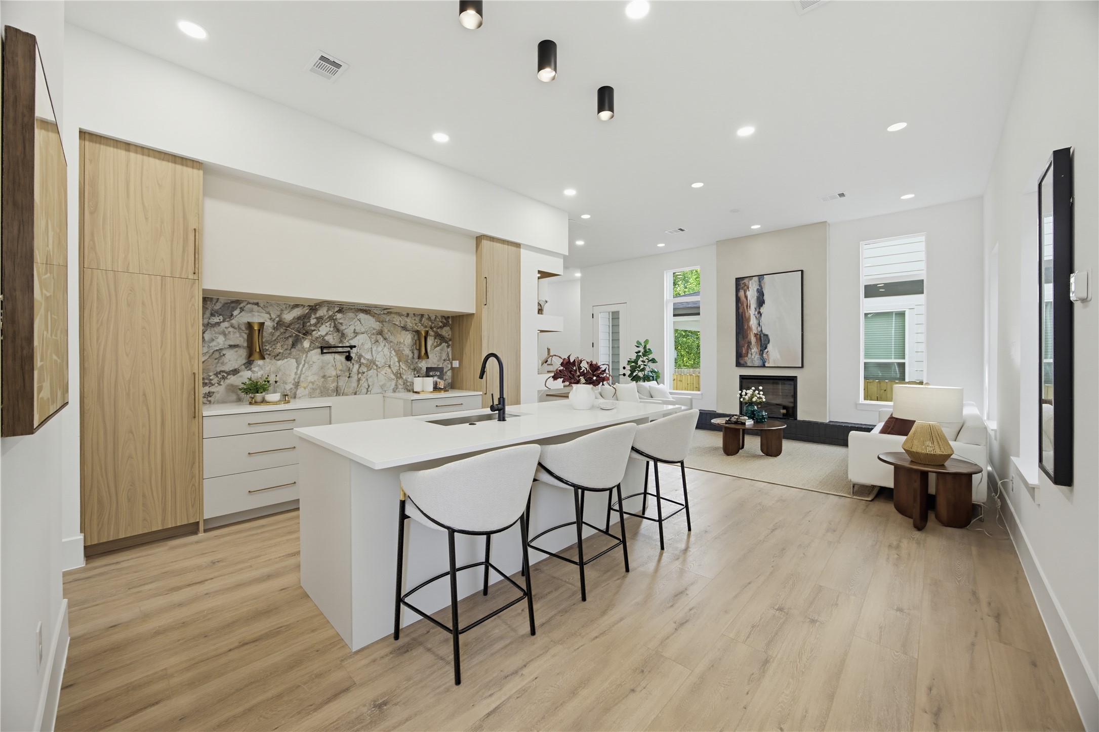 Experience modern elegance in this open-concept kitchen and living area, featuring sleek cabinetry, a stylish waterfall island, and abundant natural light. Experience modern elegance in this open-concept kitchen and living area, featuring sleek cabinetry, a stylish waterfall island, and abundant natural light.