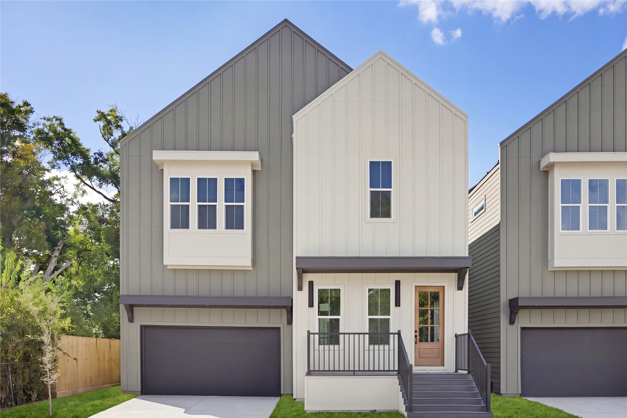 Modern two-story home with a sleek facade, featuring a welcoming front porch, stylish siding, and a spacious two-car garage.