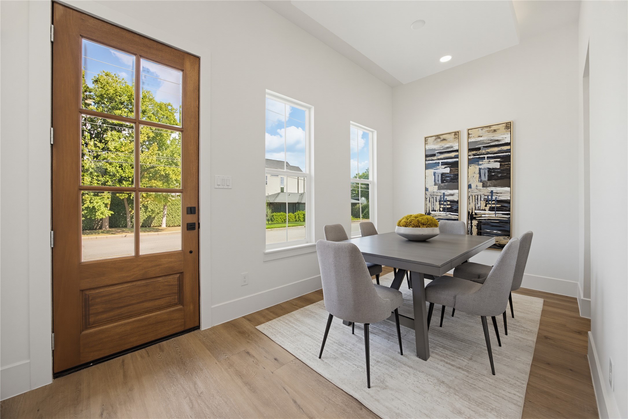 Bright and cozy dining area complemented by large windows and a stylish wooden door, creating a welcoming atmosphere. Bright and cozy dining area complemented by large windows and a stylish wooden door, creating a welcoming atmosphere.