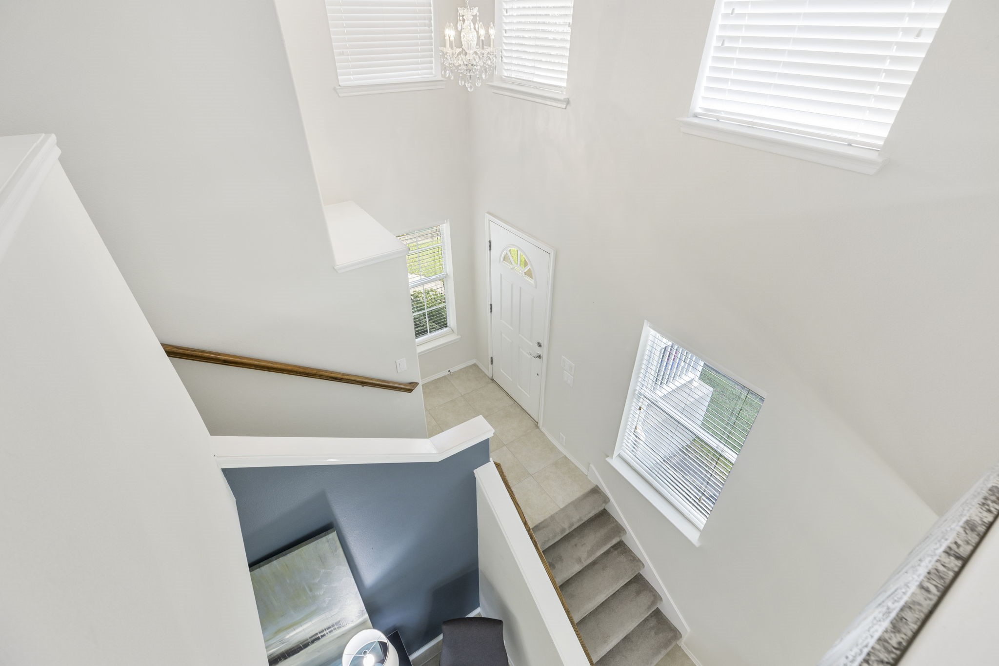The bright and airy staircase with high ceilings, large windows, and elegant chandelier makes a grand first impression.