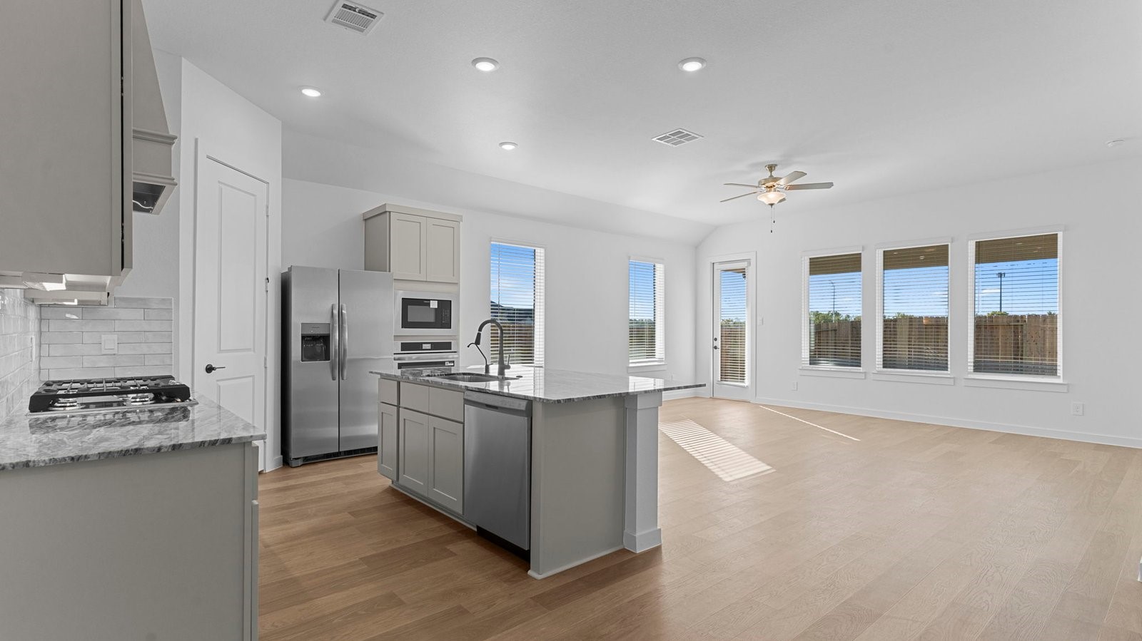 Bright and spacious kitchen with quartz countertops, stainless steel appliances, and an island with bar seating.