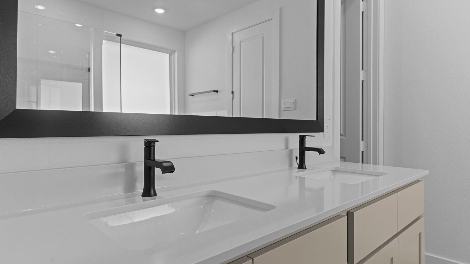 primary bathroom with double vanities, quartz countertops, and a glass-enclosed shower with a walk-in closet.