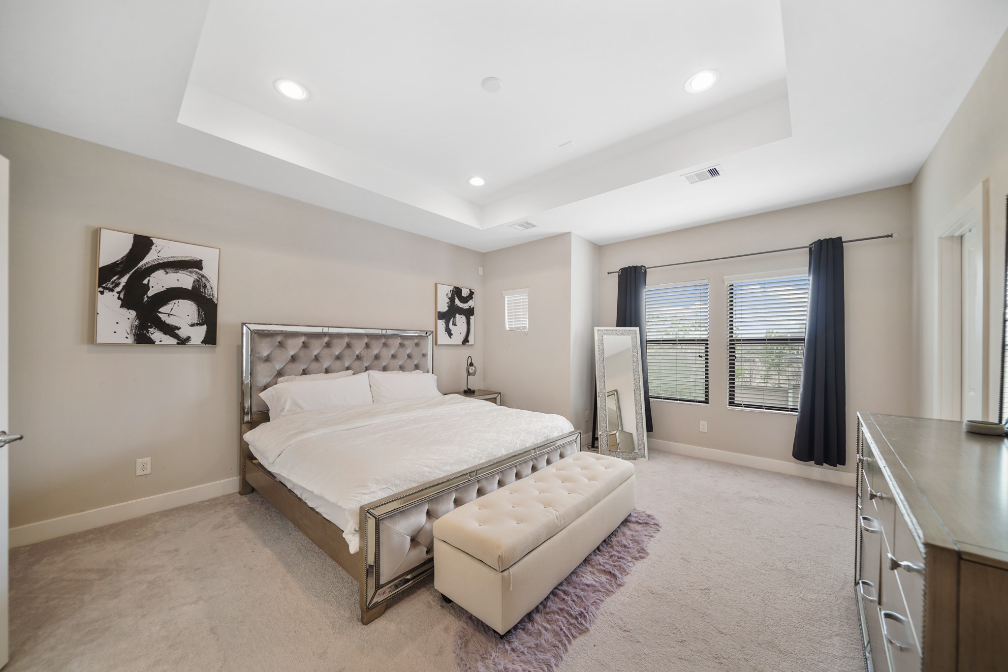The primary suite includes a high tray ceiling with recessed
lighting, pre-wiring for a ceiling fan, windows with blinds & drapes overlooking the side of the home, one of two walk-in wardrobe storage closets & carpet.