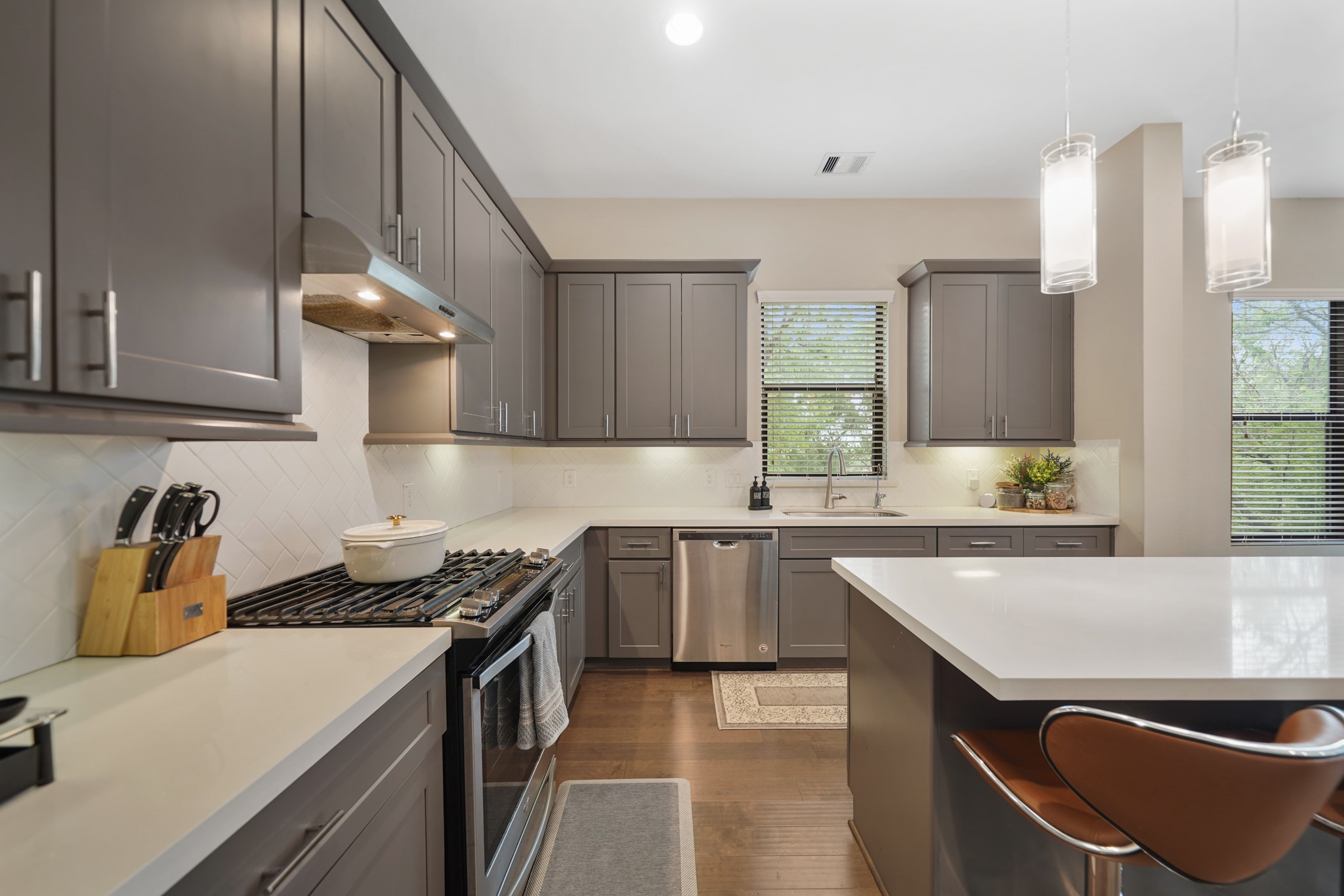 A single basin stainless steel under mount sink sits below a window with blinds. This home includes a complete water filtration system along with a reverse osmosis filtration system at the kitchen sink.