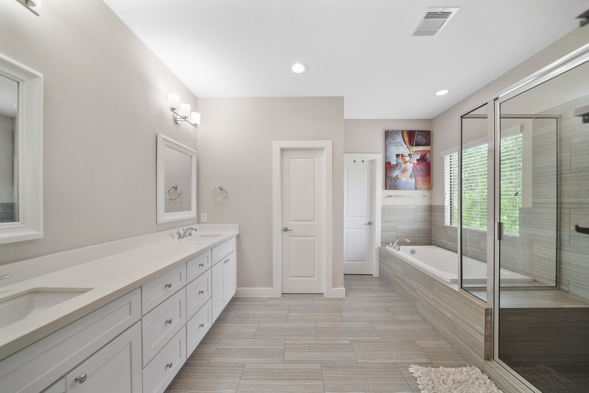 Luxury awaits you in this well appointed private bath with recessed lighting, painted Shaker-style cabinets supporting a quartz counter top with dual under-mount sinks and framed mirrors with wall mounted lighting above.
