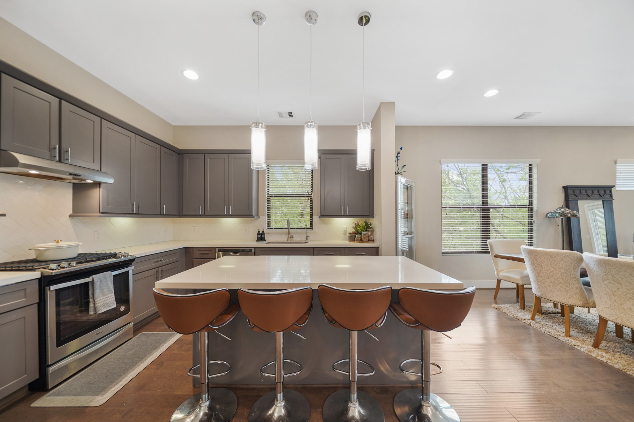 The centrally located island illuminated by pendant lighting offers breakfast bar seating and doubles as a serving bar. Included is a stainless steel beverage fridge tucked away just below the island.