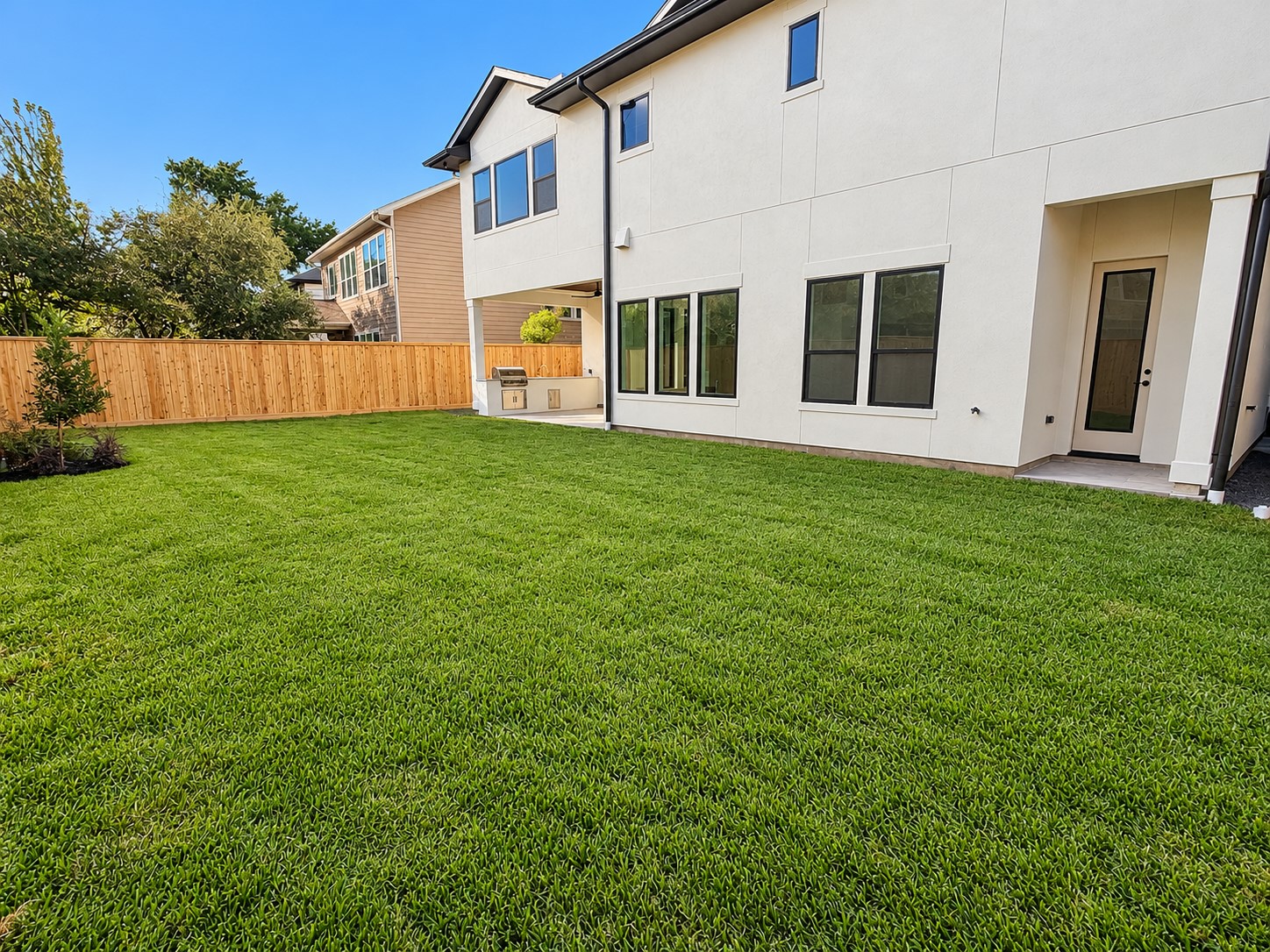 The backyard has plenty of room for a pool. The small porch to the right is to the pool bath, and the outdoor living with Summer kitchen is on the left end of the home.