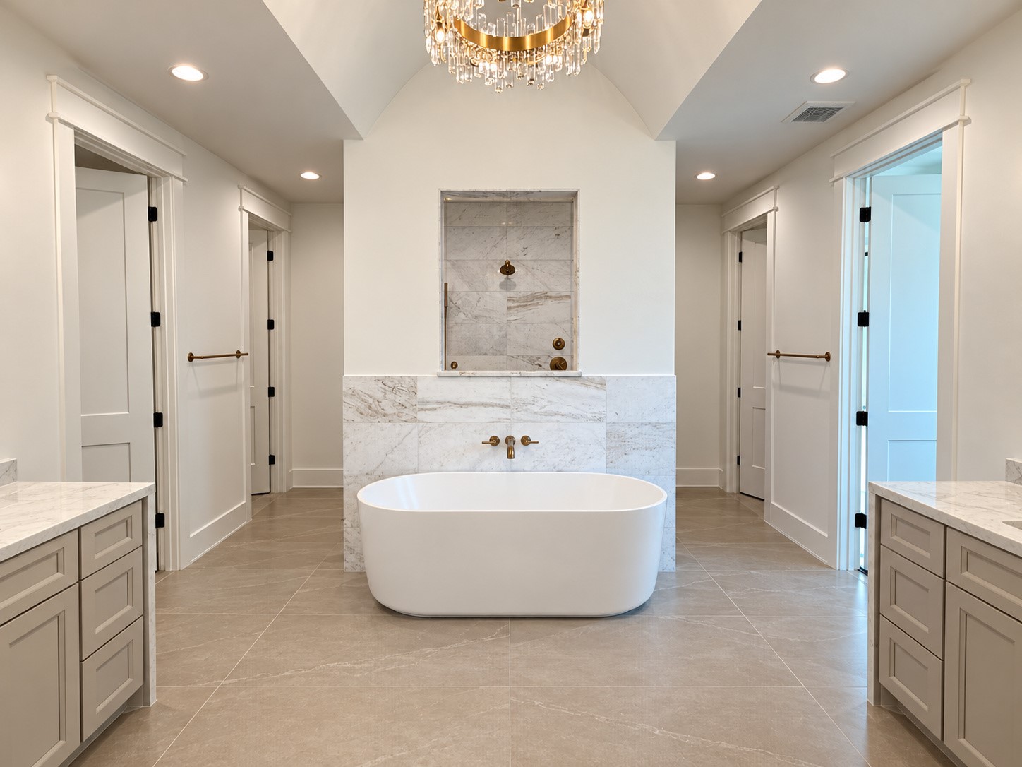 This gorgeous symmetrical bathroom features his and her vanities, closets, and water closets. The fluted freestanding tub makes a statement in front of the dual-entry shower.