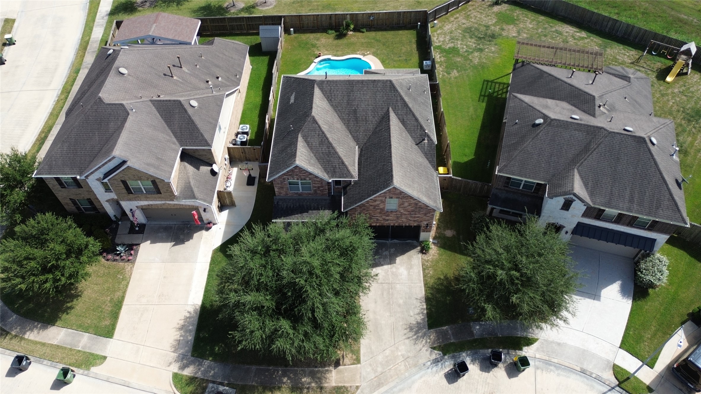 Drone view of pool, green space, and front access