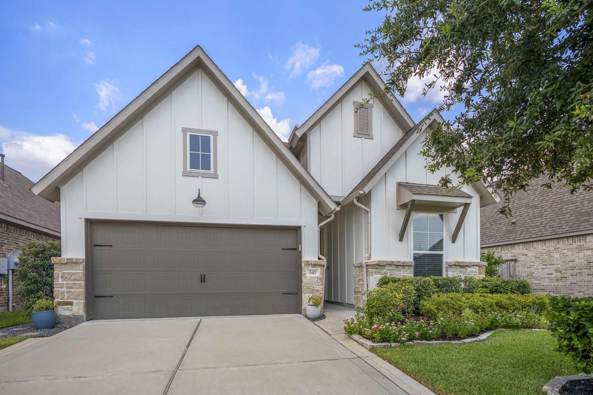 Home features a covered entryway, lush landscaping, full sprinkler system and extended driveway.