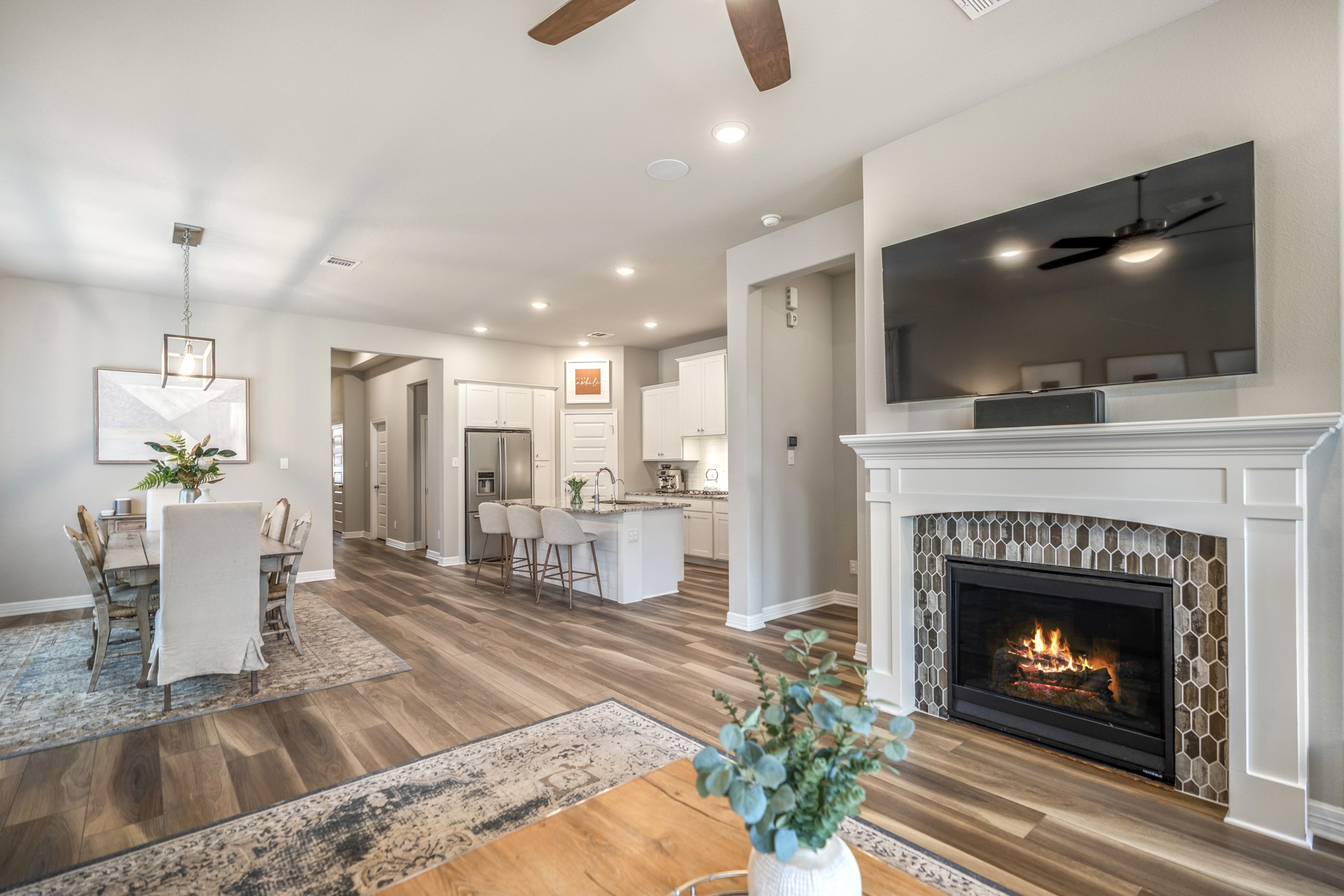 Spacious living room with luxury vinyl plank flooring throughout and a cozy gas fireplace featuring the most beautiful tile surround.