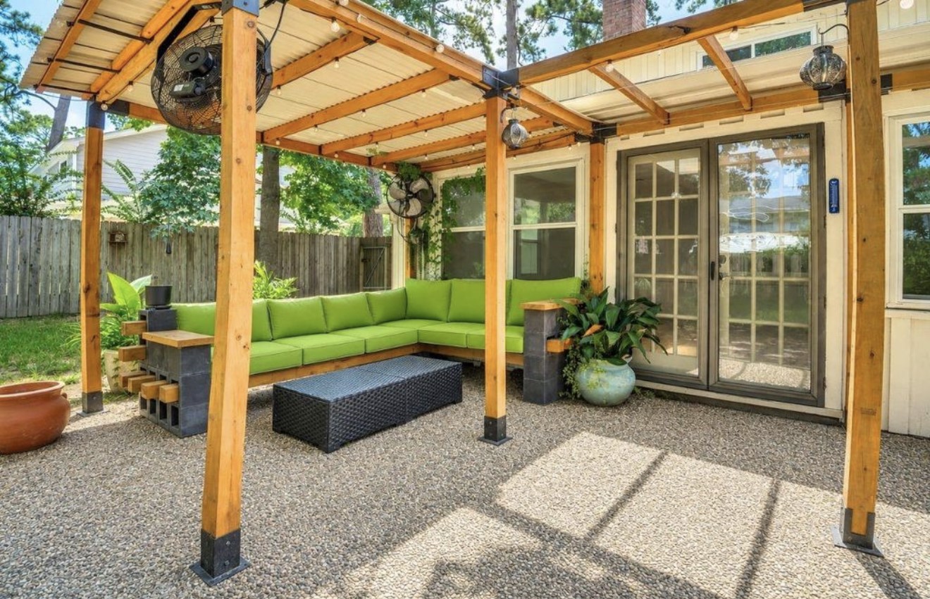Inviting covered outdoor living area featuring a custom wood pergola, built-in seating, string lights, and fans for added comfort. The perfect space to relax, unwind, or entertain while enjoying the privacy of the backyard.