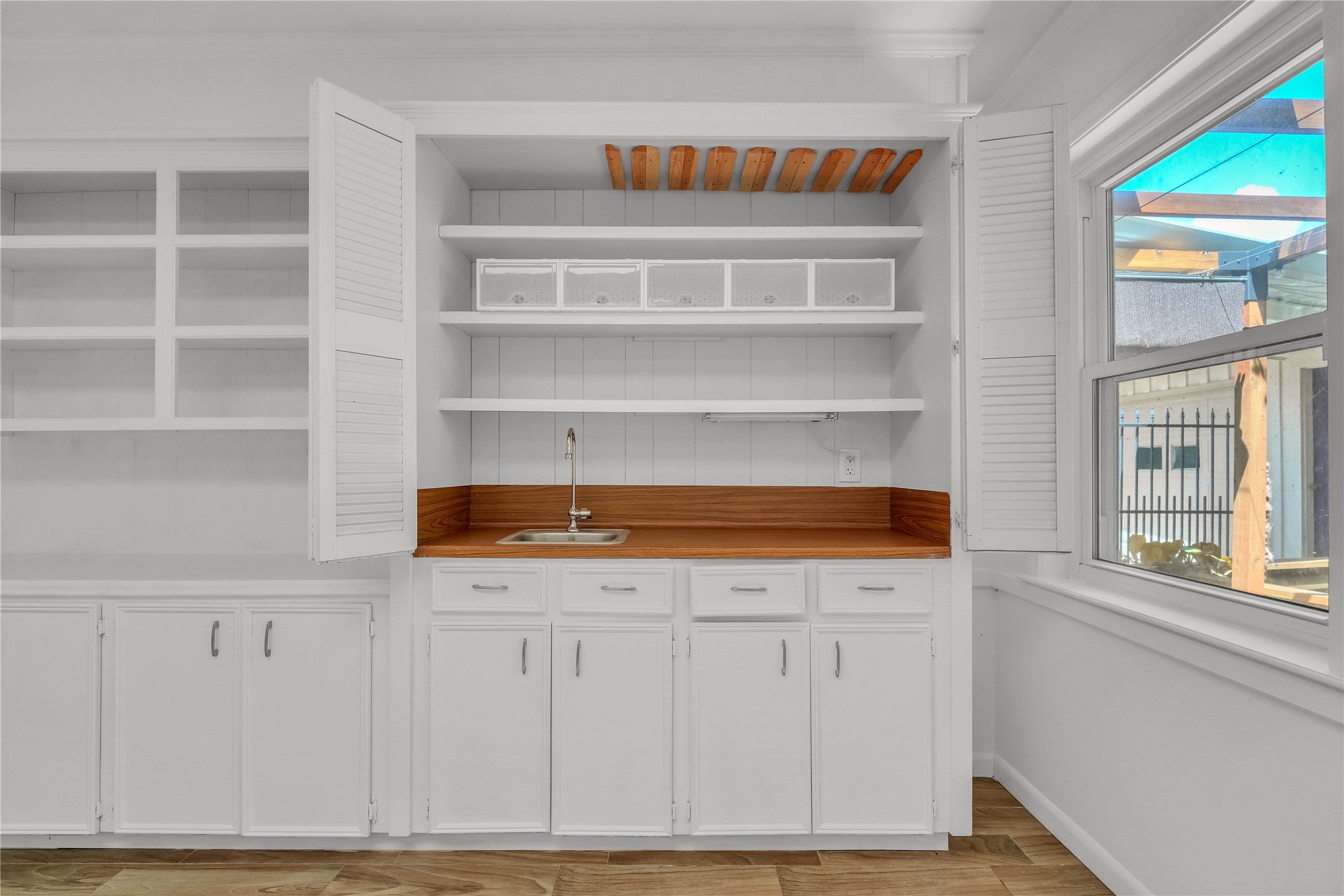 Built-in cabinetry and shelving offer ample storage and display space, complemented by a convenient sink area within the sunroom.