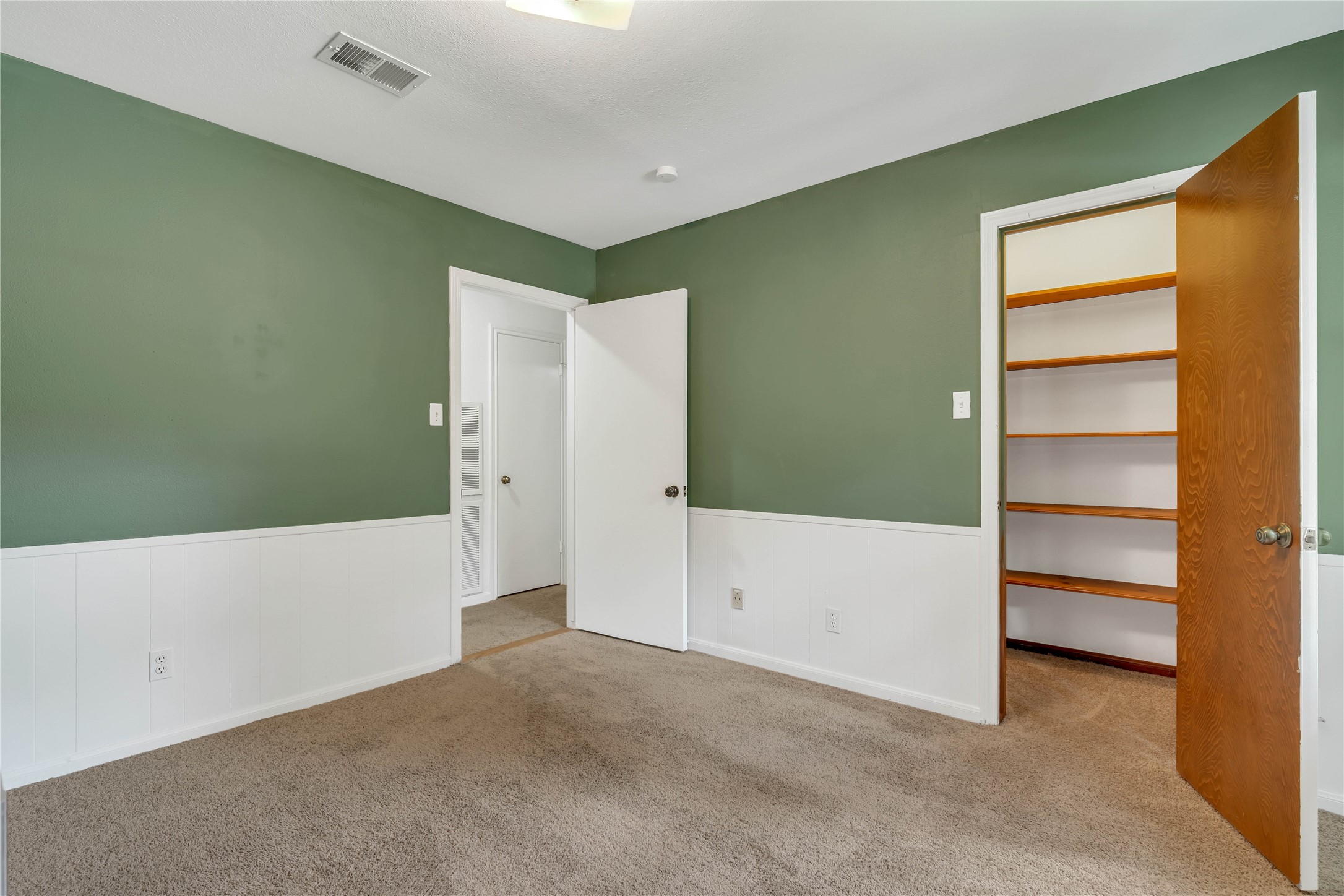 Additional upstairs bedroom featuring a dedicated closet with built-in shelving.