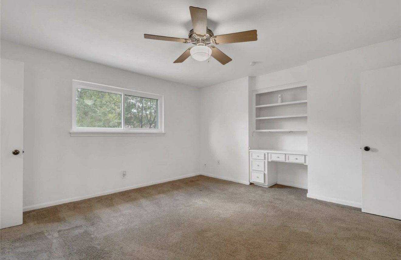 Upstairs secondary primary suite offering a private retreat with natural light, built-in shelving, and an en-suite bath, creating a well-appointed second primary space.