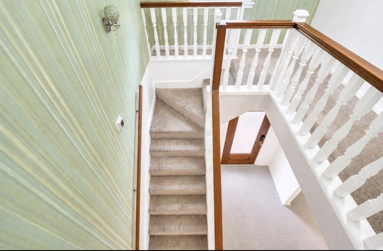 This perspective highlights the upper-level staircase with classic wood handrails and crisp white balusters, creating an open transition between the upper and main levels.