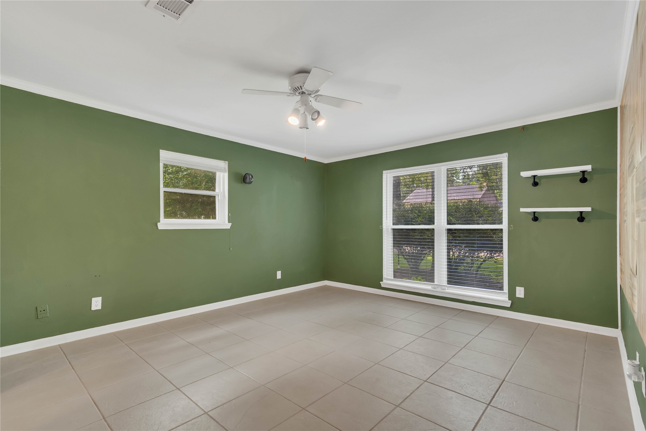 Expansive primary bedroom offering impressive proportions, abundant natural light from a wide set of windows, and a distinctive accent wall adding warmth and architectural character.
