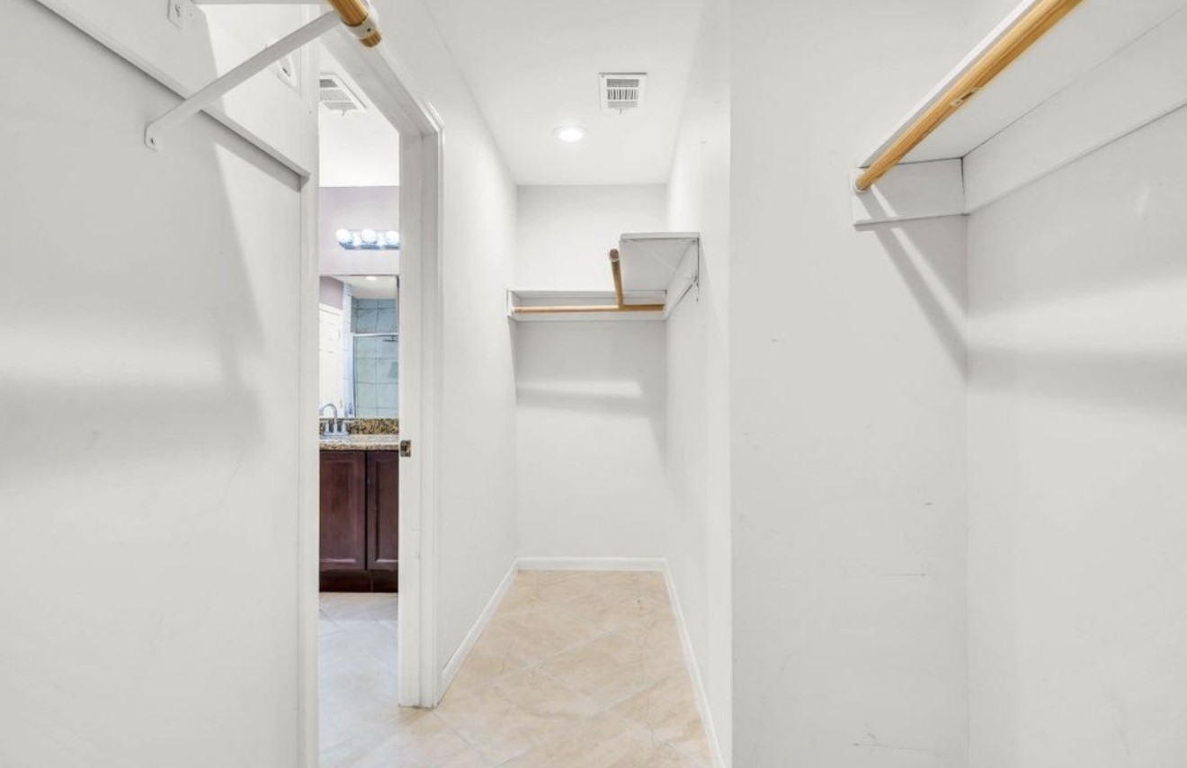 This perspective highlights the primary walk-in closets impressive depth, built-in storage, and direct connection to the primary bath.