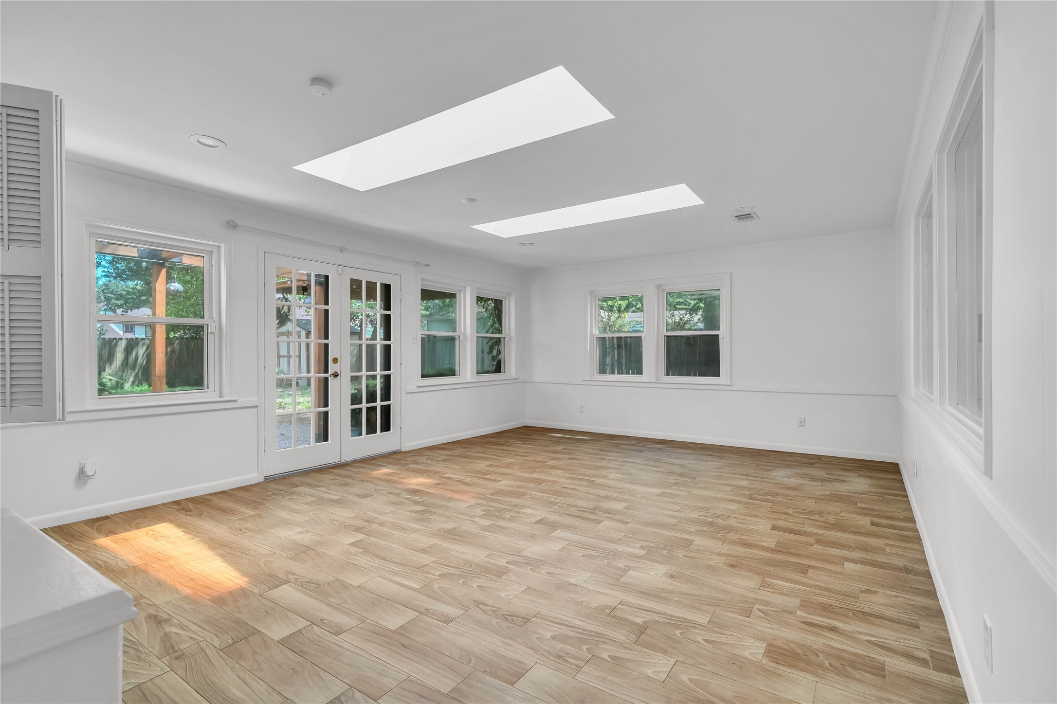 Expansive Light-filled sunroom featuring abundant windows, skylights, and an open, versatile layout.