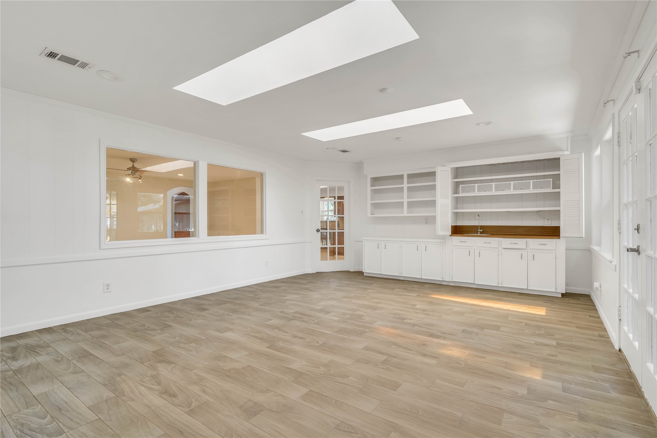 This perspective highlights the sunrooms generous size, abundant natural light from multiple windows and skylights, built-in storage, and flexible layout, ideal for a game room, playroom, hobby space, or additional entertaining area.
