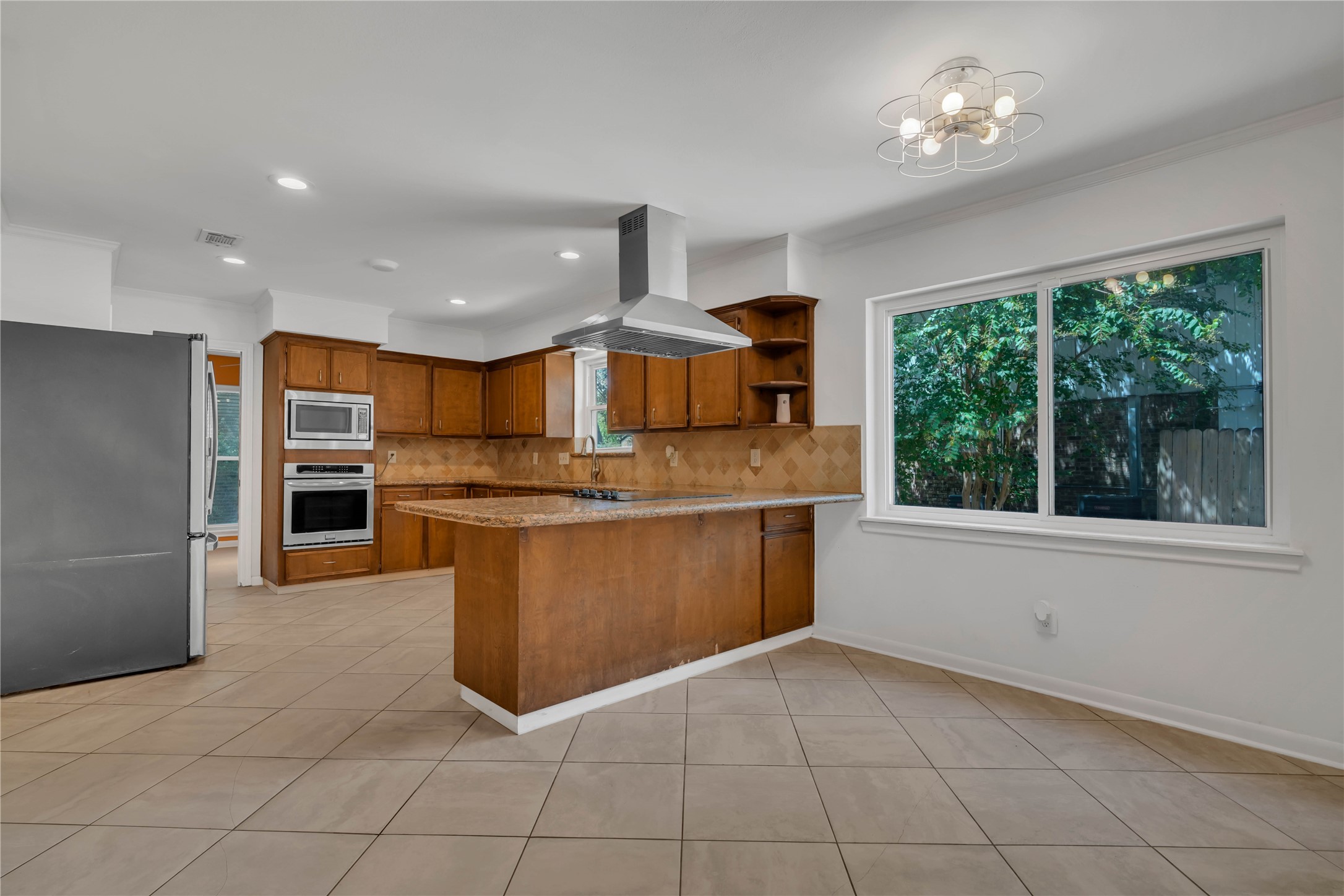 Spacious breakfast room filled with natural light, positioned just off the kitchen with views of the granite peninsula, abundant cabinetry, and cooktop.