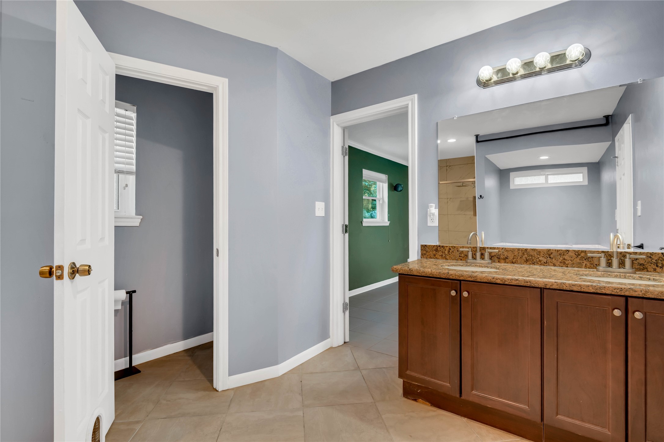 The primary bath also features a double vanity with granite countertops, ample counter space, and convenient cabinetry for storage.