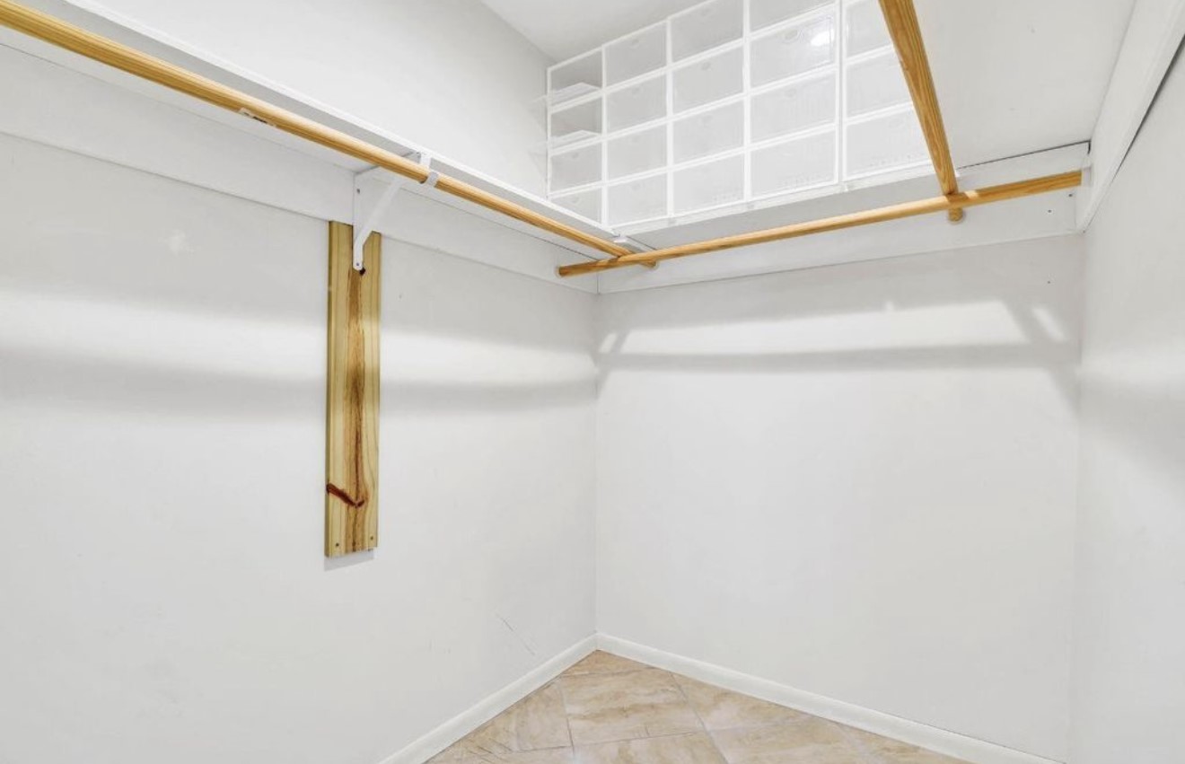 Spacious primary walk-in closet featuring extensive built-in shelving and multiple hanging areas for organized storage.