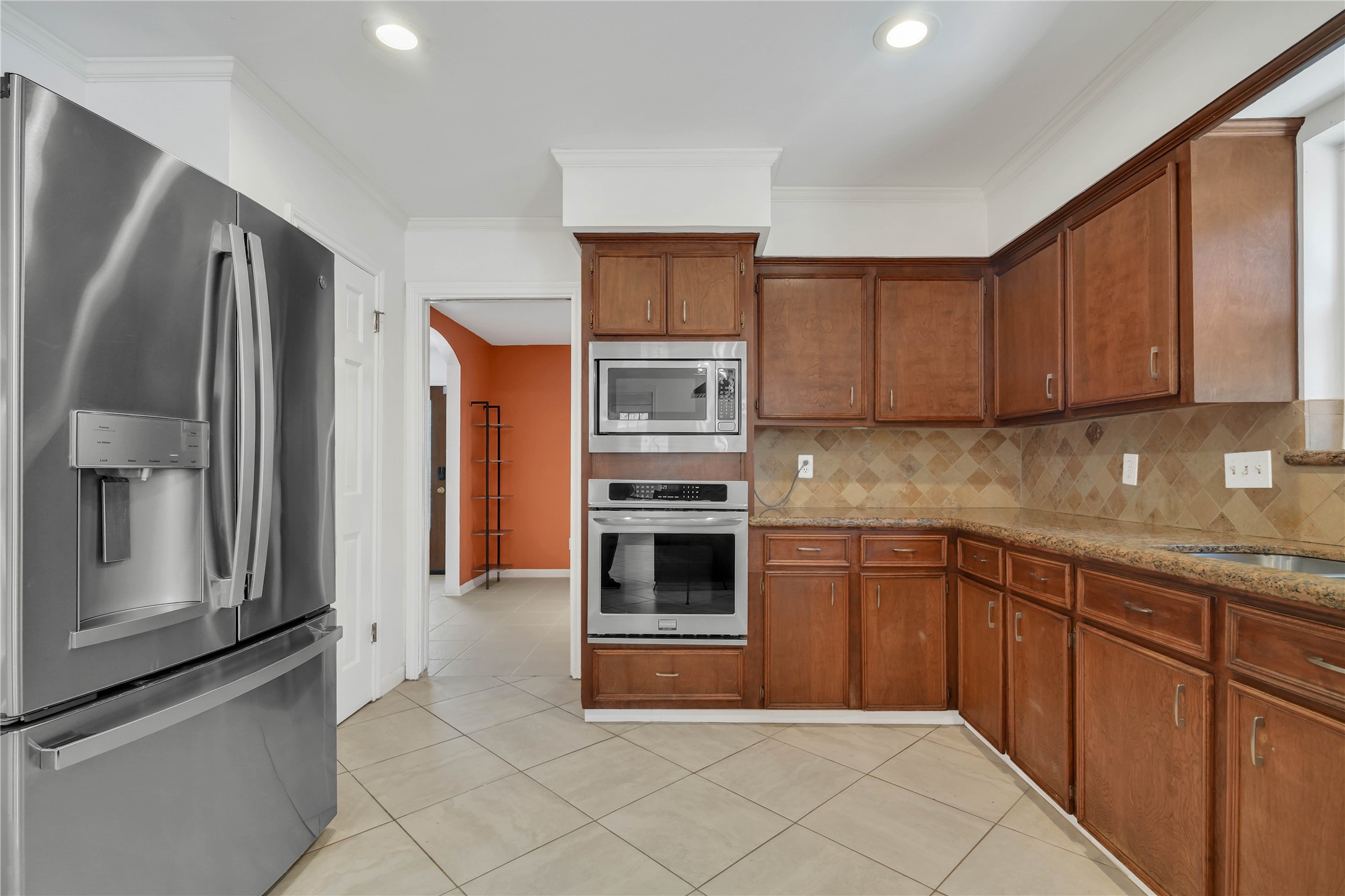 Spacious kitchen featuring granite countertops, abundant cabinetry, stainless steel appliances, and built-in double ovens, with a view into the adjoining formal dining room.