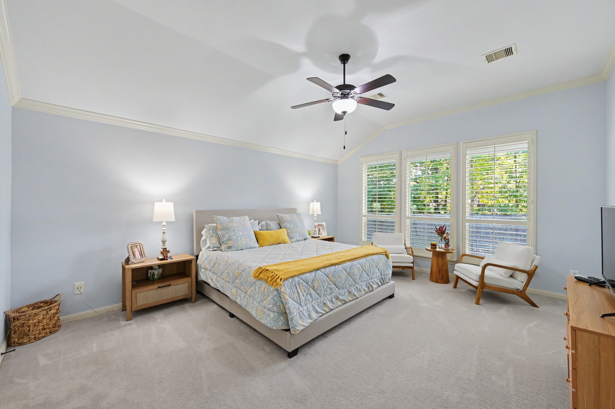 Spacious bedroom with soft blue walls, large windows allowing natural light, and a cozy seating area, creating a serene retreat.