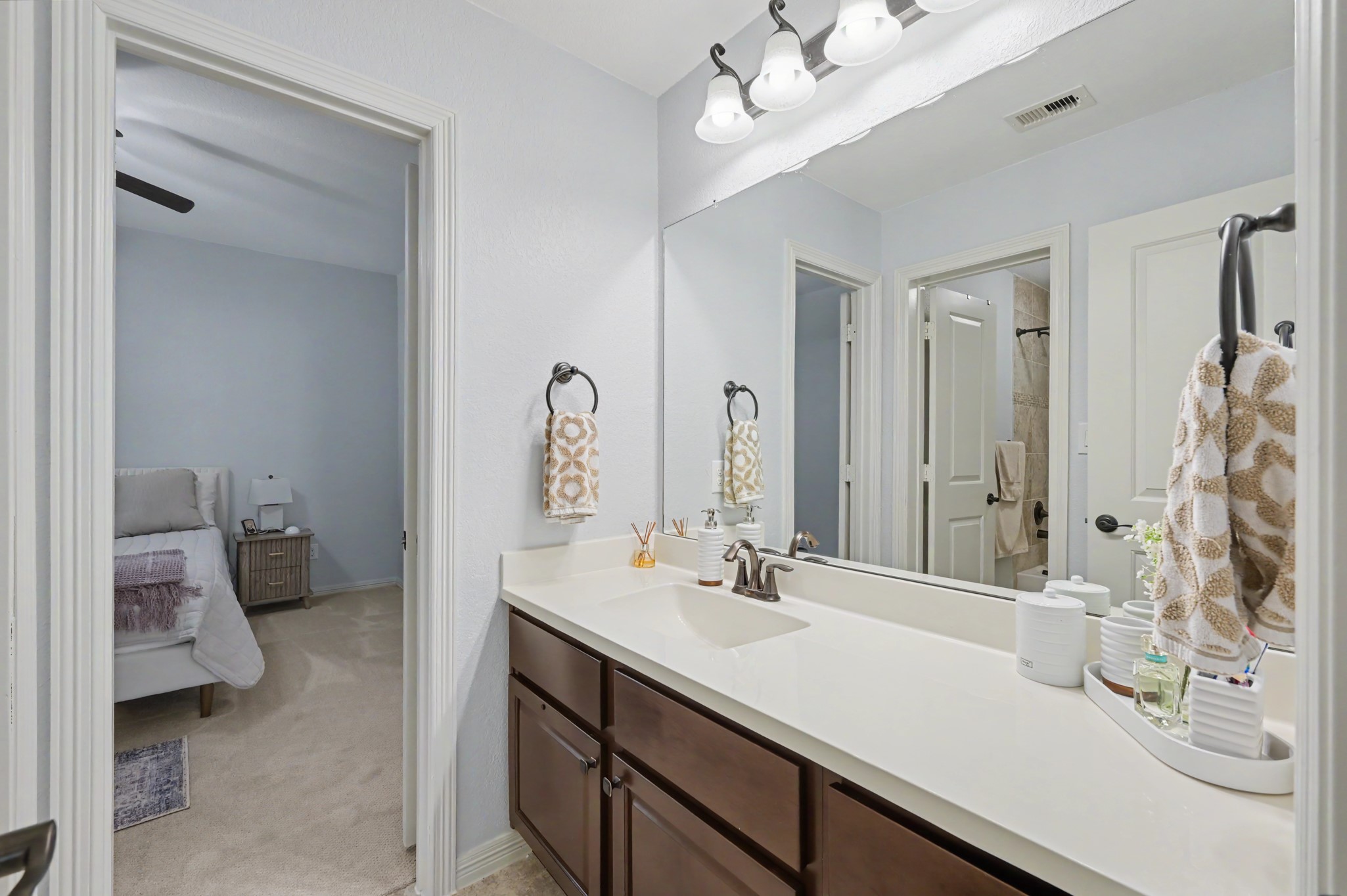 Elegant bathroom featuring a spacious dual-sink vanity, modern lighting, and direct access to a cozy bedroom.