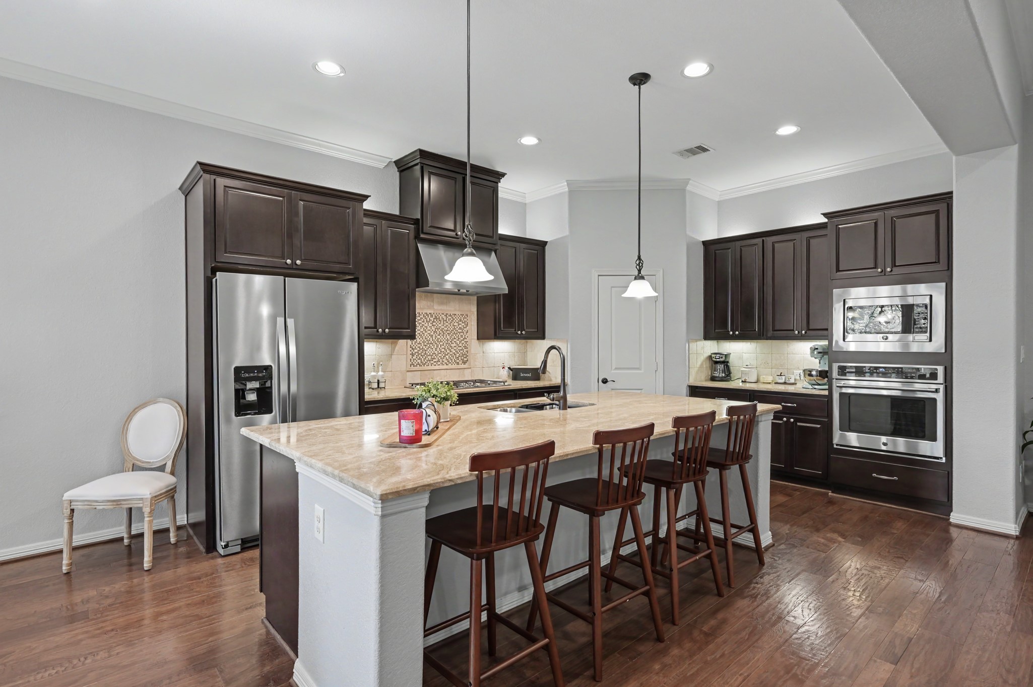 Elegant kitchen featuring rich dark wood cabinets, stainless steel appliances, and a spacious island with seating, perfect for entertaining.