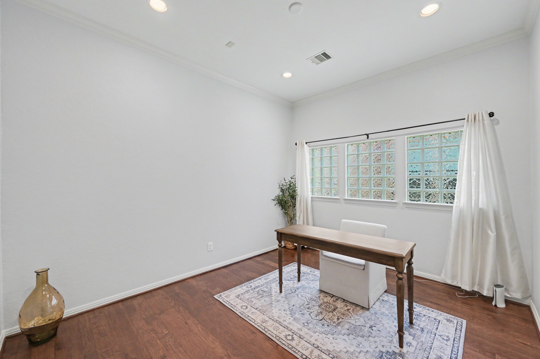 Bright and inviting home office with elegant wooden flooring, a large window for natural light, and a minimalist design that inspires productivity.