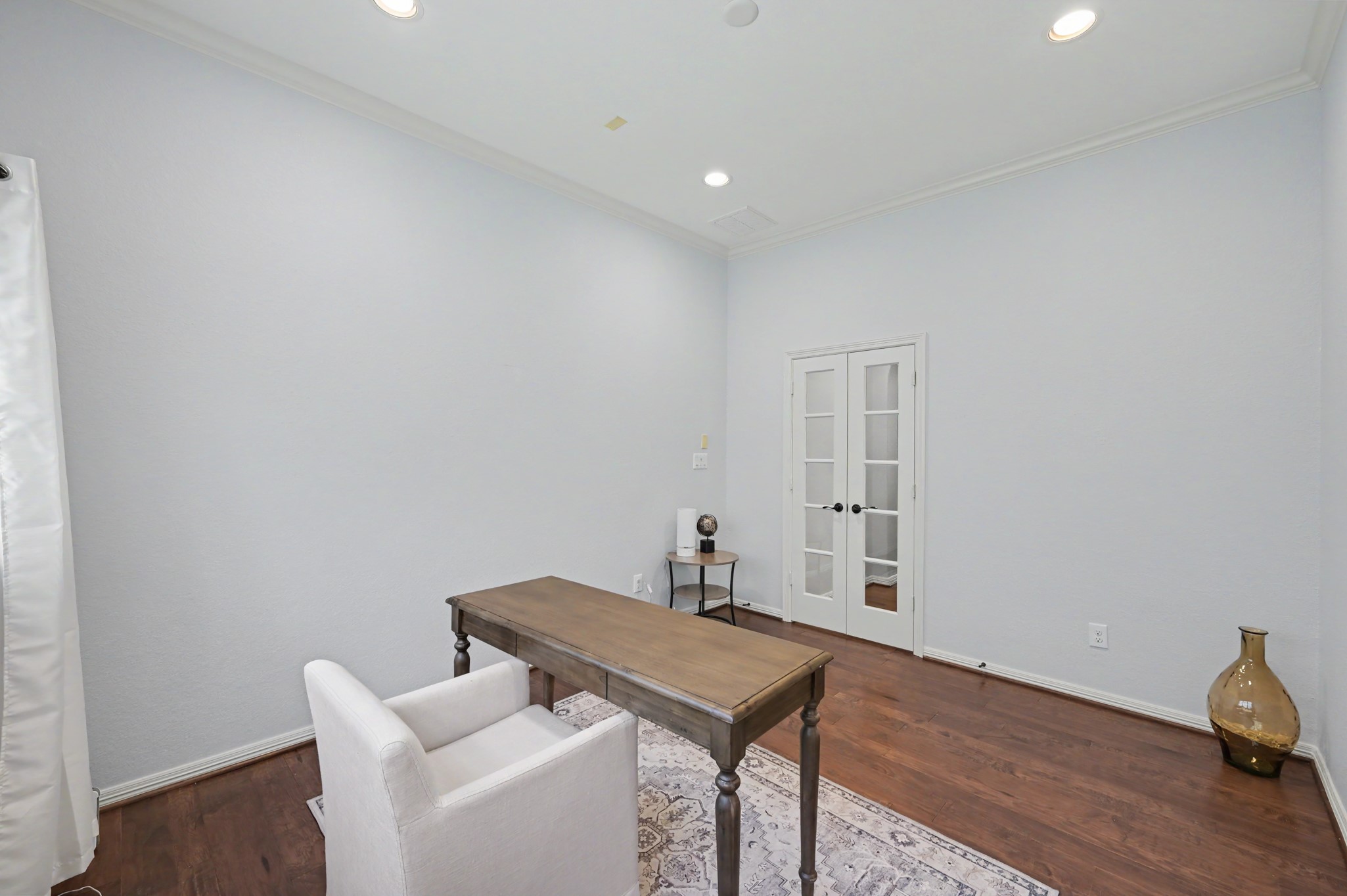 Bright and inviting home office with elegant French doors, rich hardwood floors, and ample lighting, ideal for productivity and focus.