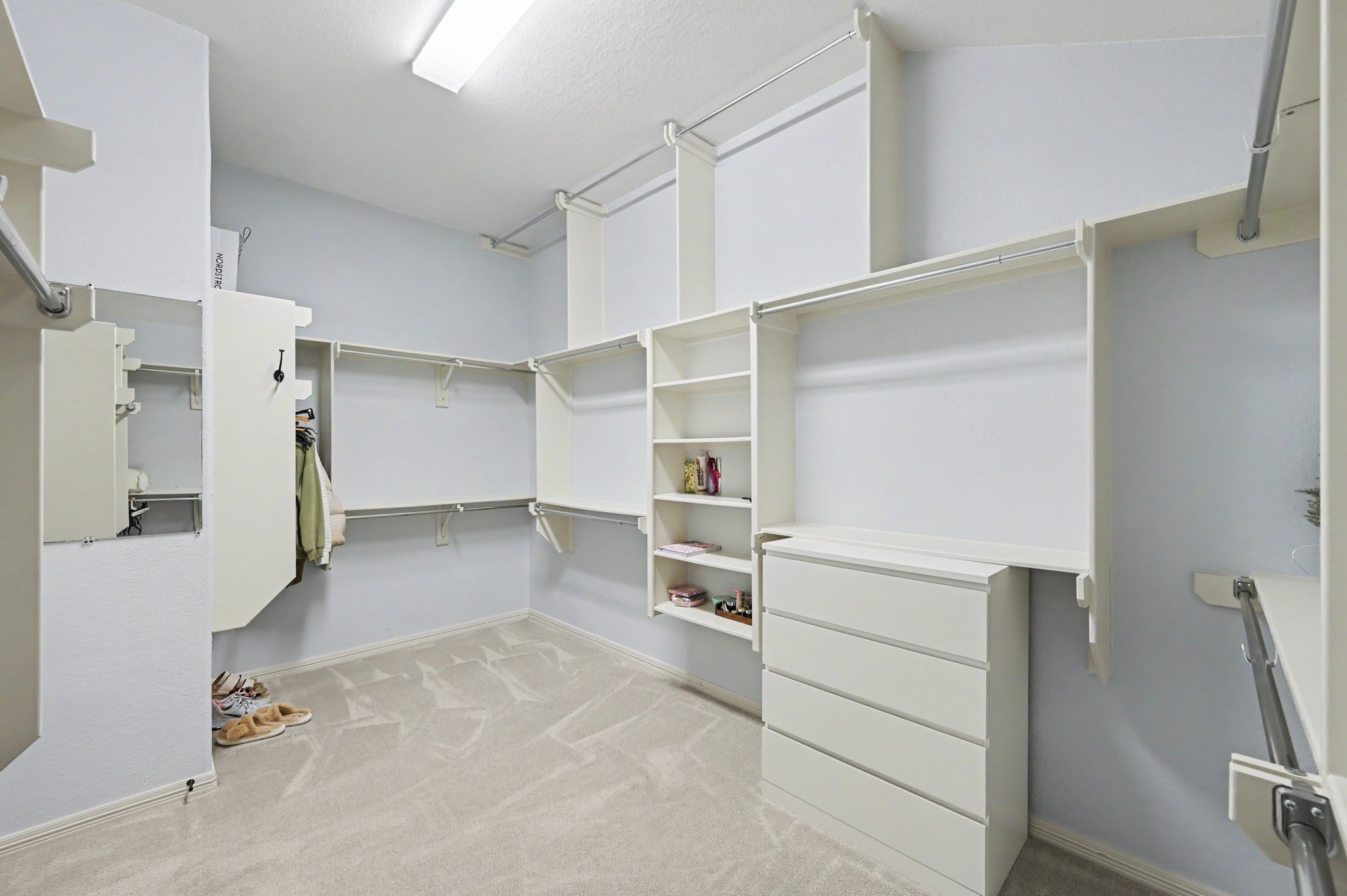Spacious walk-in closet featuring custom shelving, ample hanging space, and a built-in dresser for organized storage.