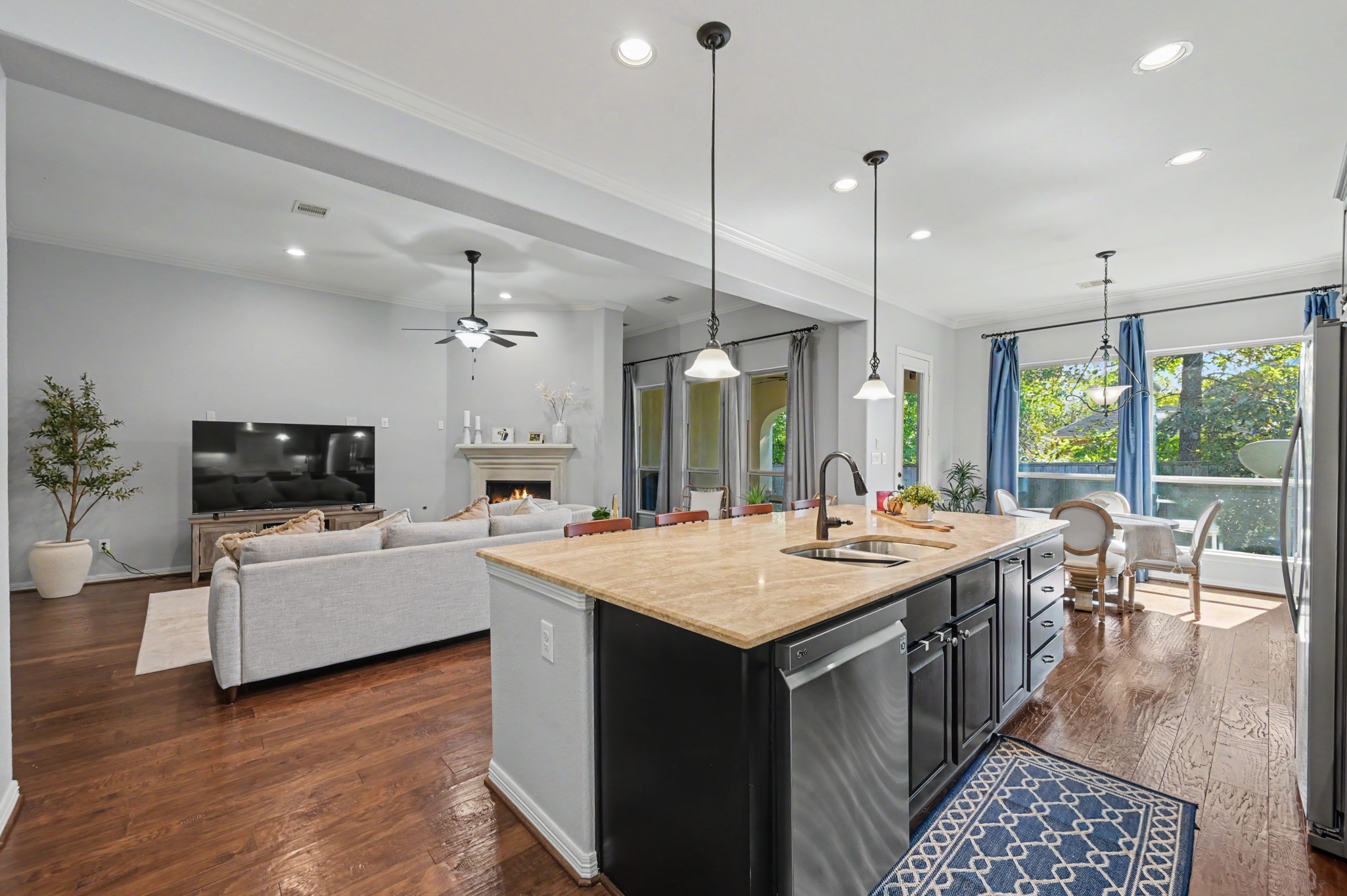 Spacious open-concept living area featuring a modern kitchen with a large island, elegant pendant lighting, and ample natural light from large windows, perfect for entertaining and family gatherings.