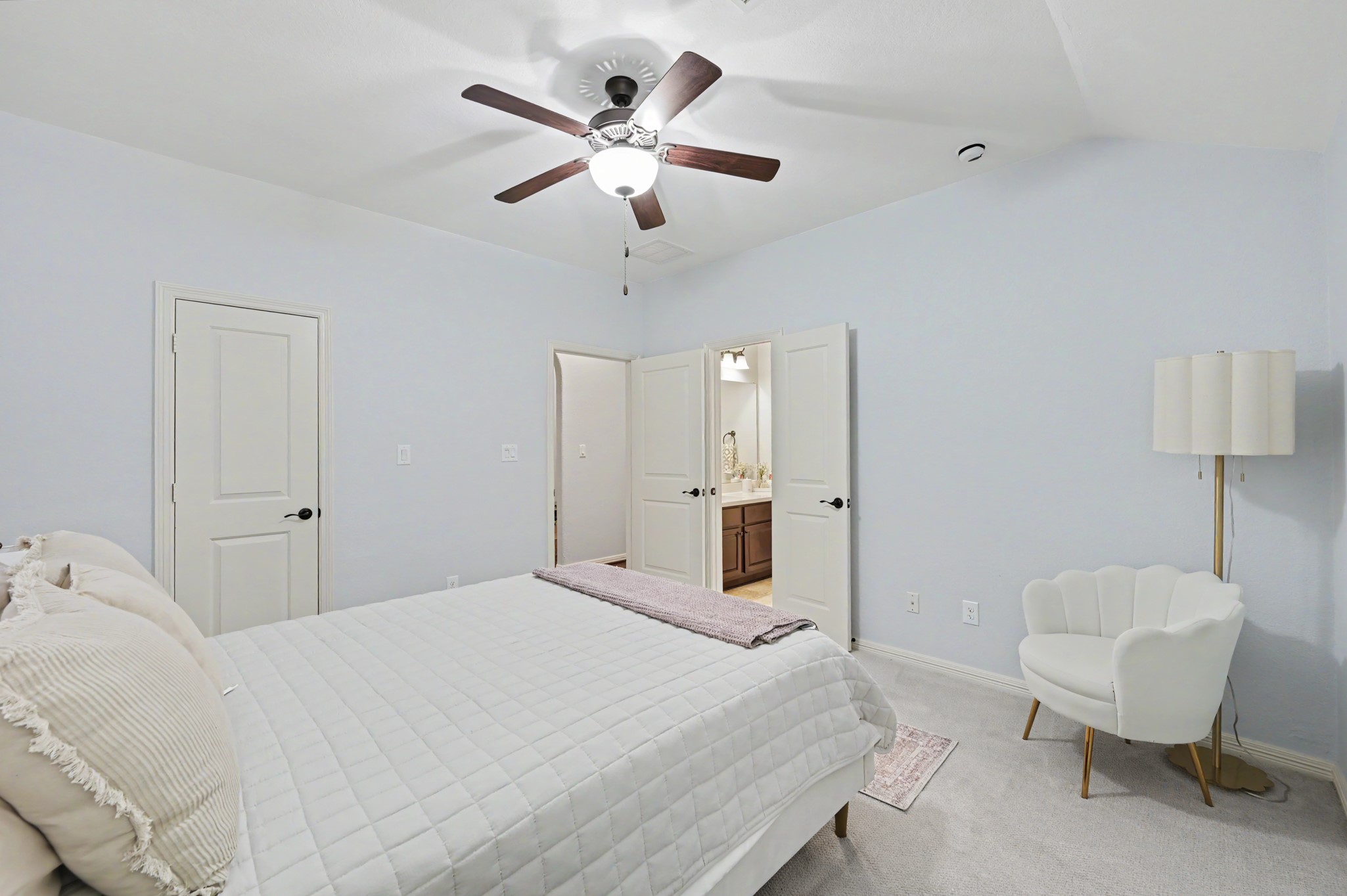 Bright and inviting bedroom with a ceiling fan, plush carpeting, and an ensuite bathroom for added convenience.