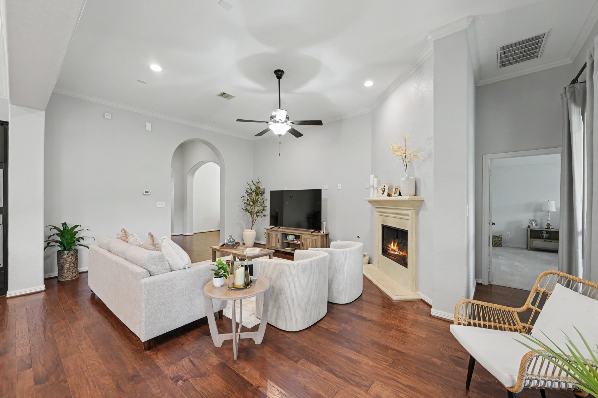 Spacious living room featuring elegant hardwood floors, a cozy fireplace, and abundant natural light, perfect for relaxation and entertaining.
