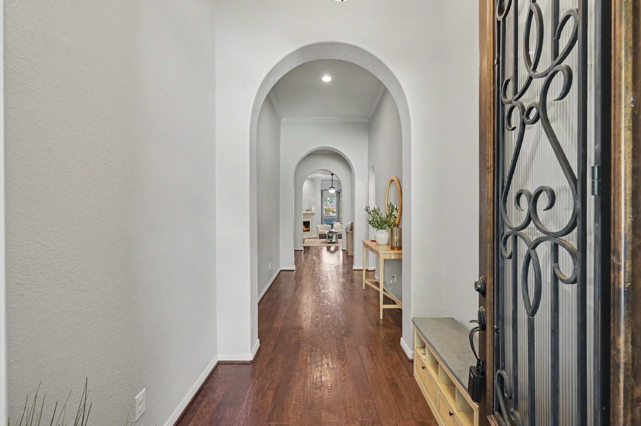 Inviting entryway with elegant arched doorways and warm hardwood floors, leading to a cozy and well-lit living area.