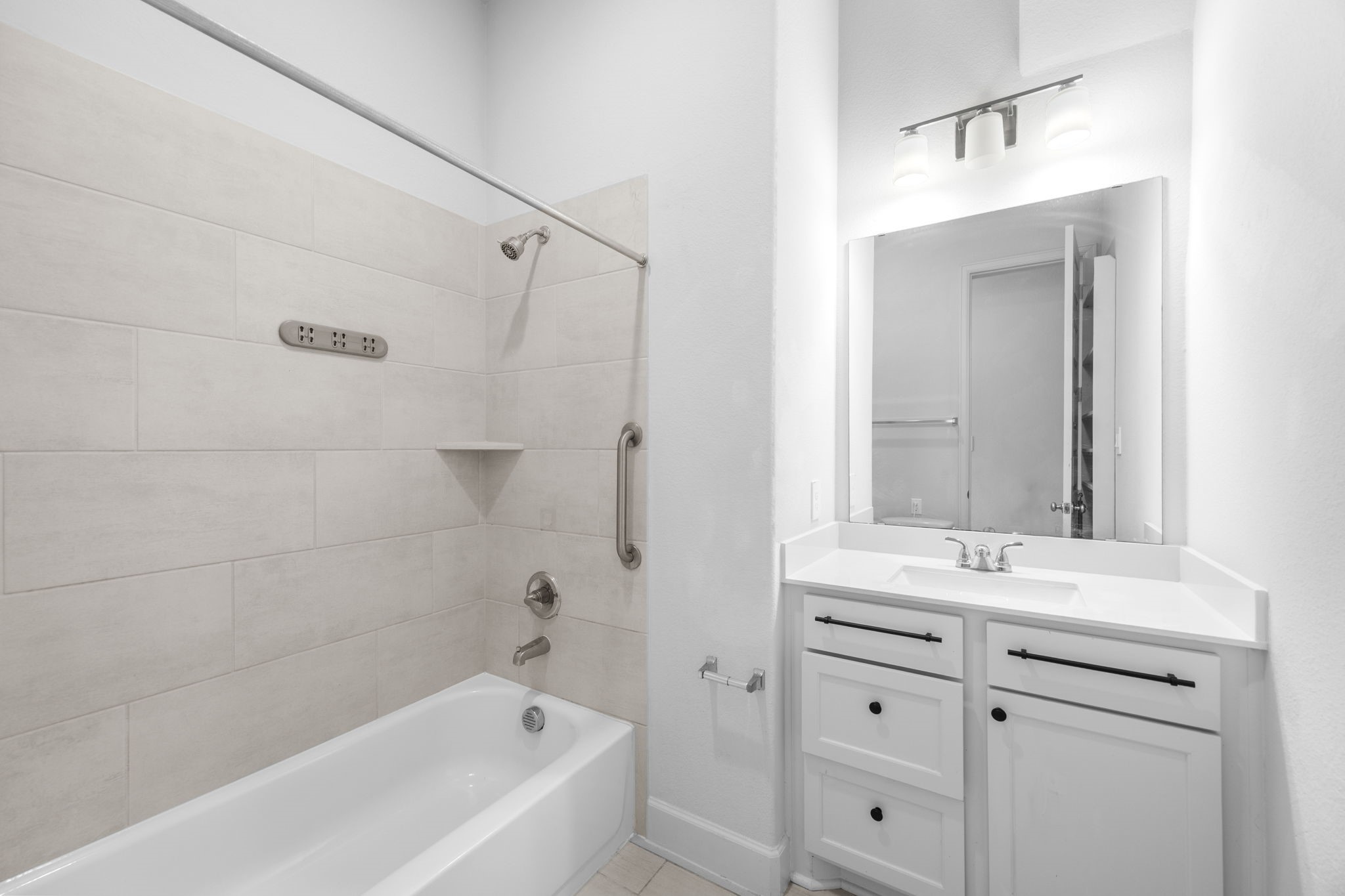 Stylish secondary bathroom with a tub and shower combination, beautiful tilework, and ample vanity storage.