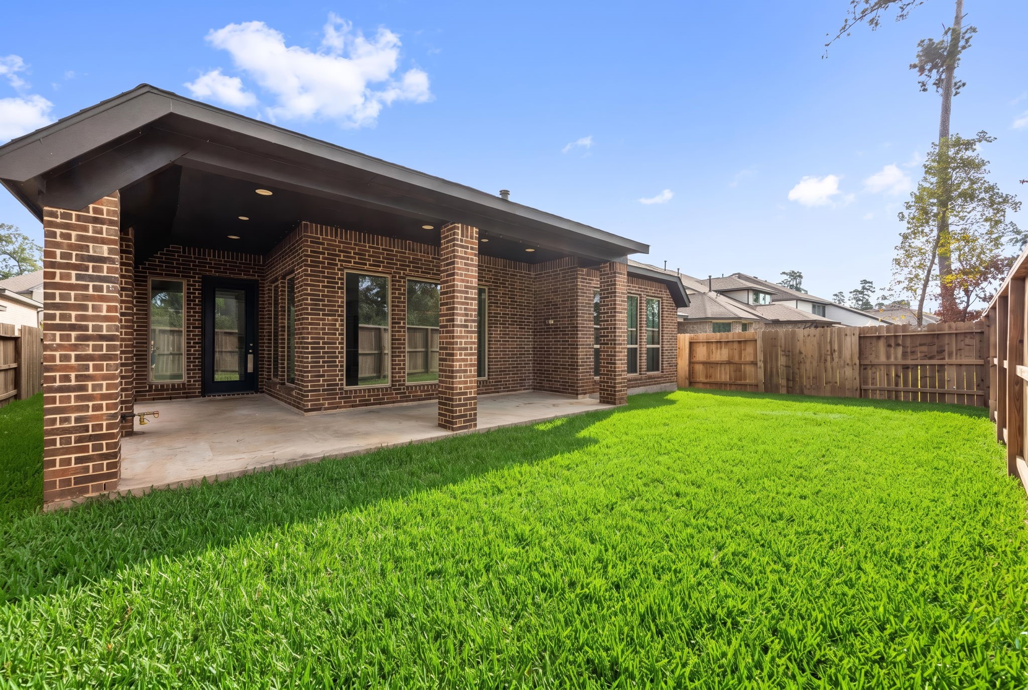 Enjoy the outdoors in this private, fully fenced backyard with lush green lawn and a spacious covered patio.