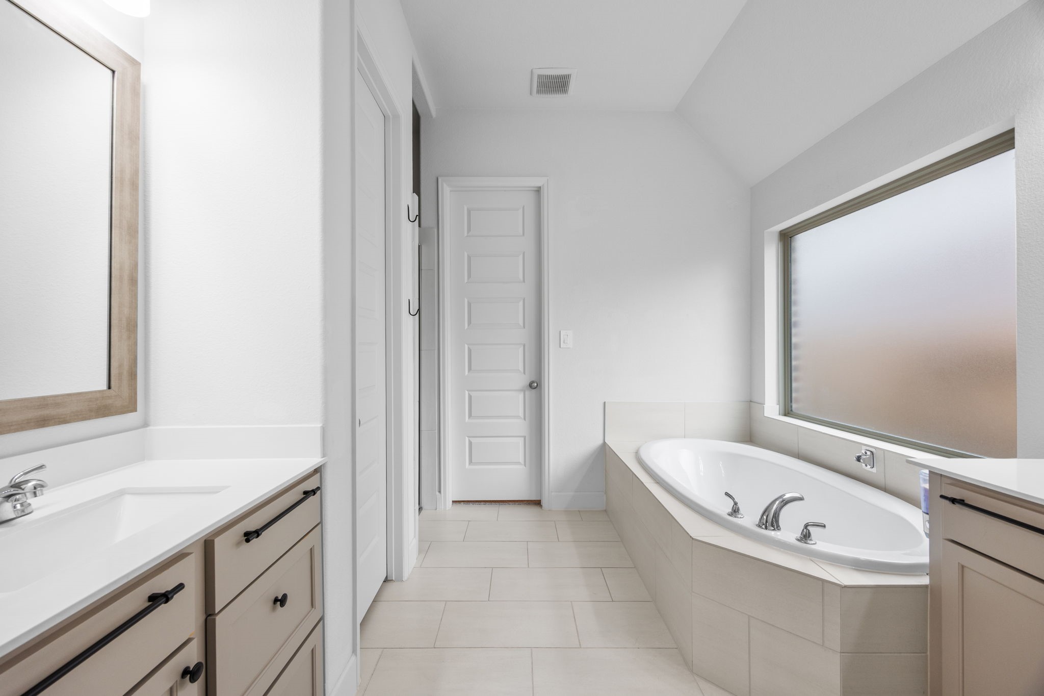 Beautifully designed bathroom featuring a soaking tub, spacious vanity, and elegant neutral finishes.