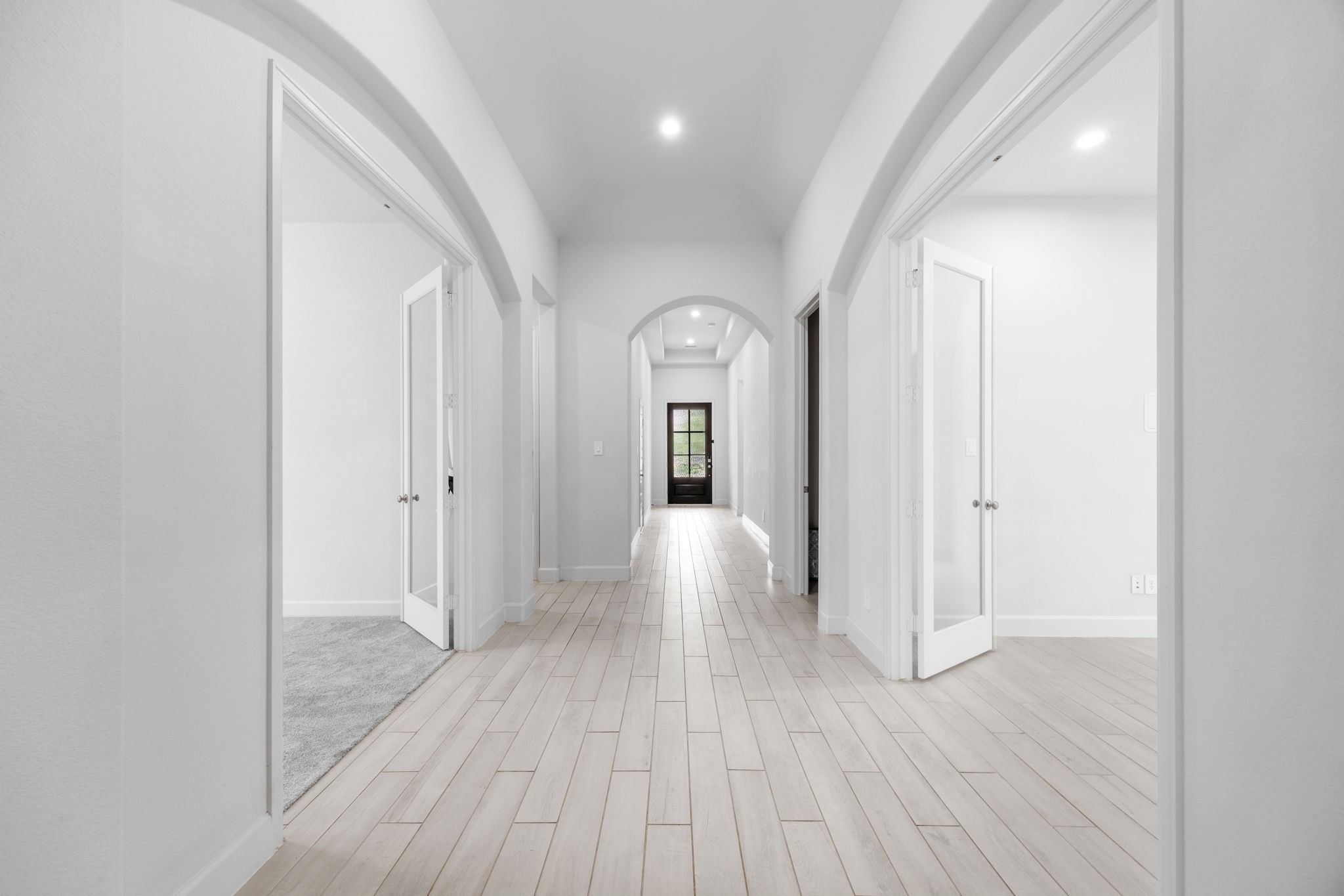Elegant entryway featuring soaring ceilings, graceful archways, and beautiful wood-look flooring.
