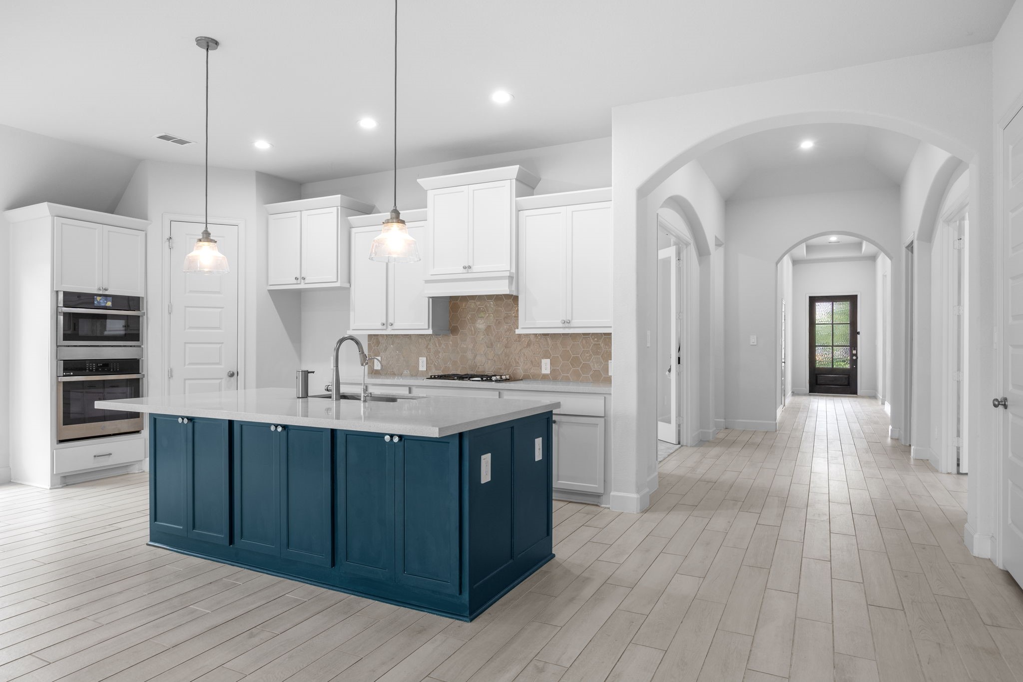 Stunning kitchen showcases a striking navy island, crisp white cabinetry, and an open, airy design.