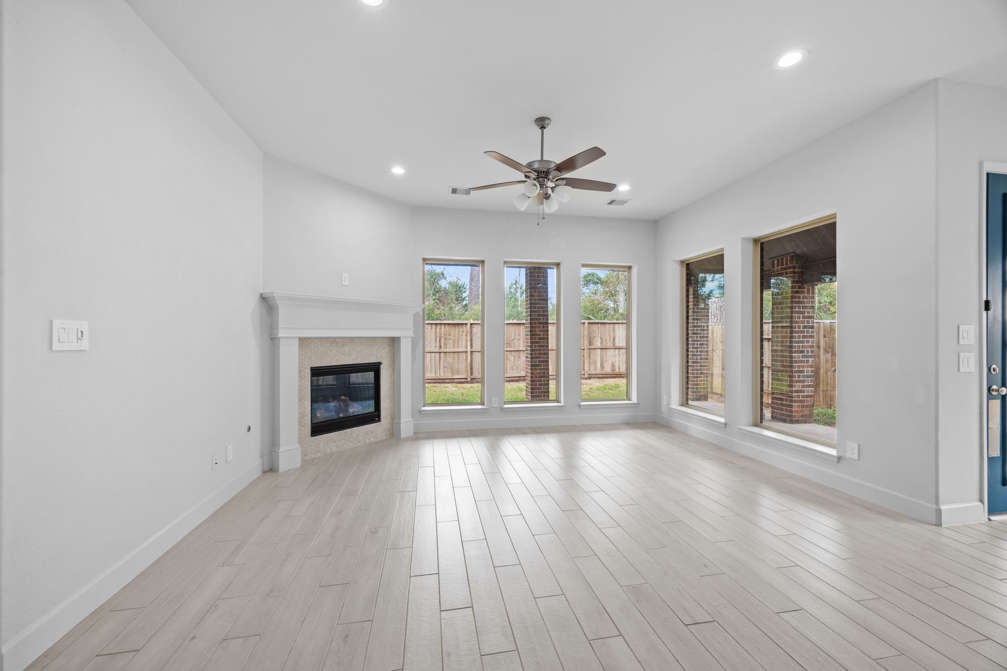 Bright and spacious living room featuring a cozy fireplace, high ceilings, and beautiful flooring.