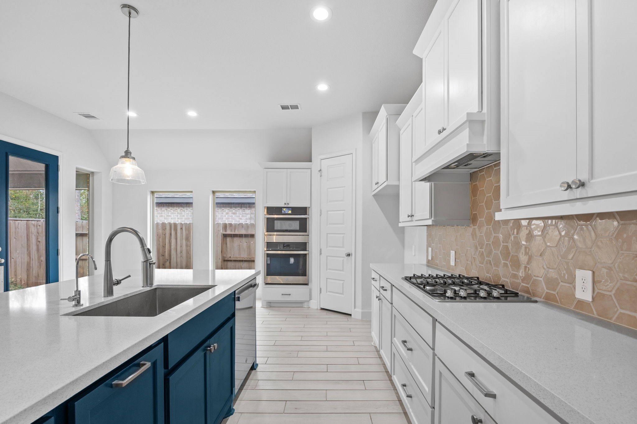 Thoughtfully designed kitchen featuring beautiful countertops, pendant lighting, and custom-style cabinetry.