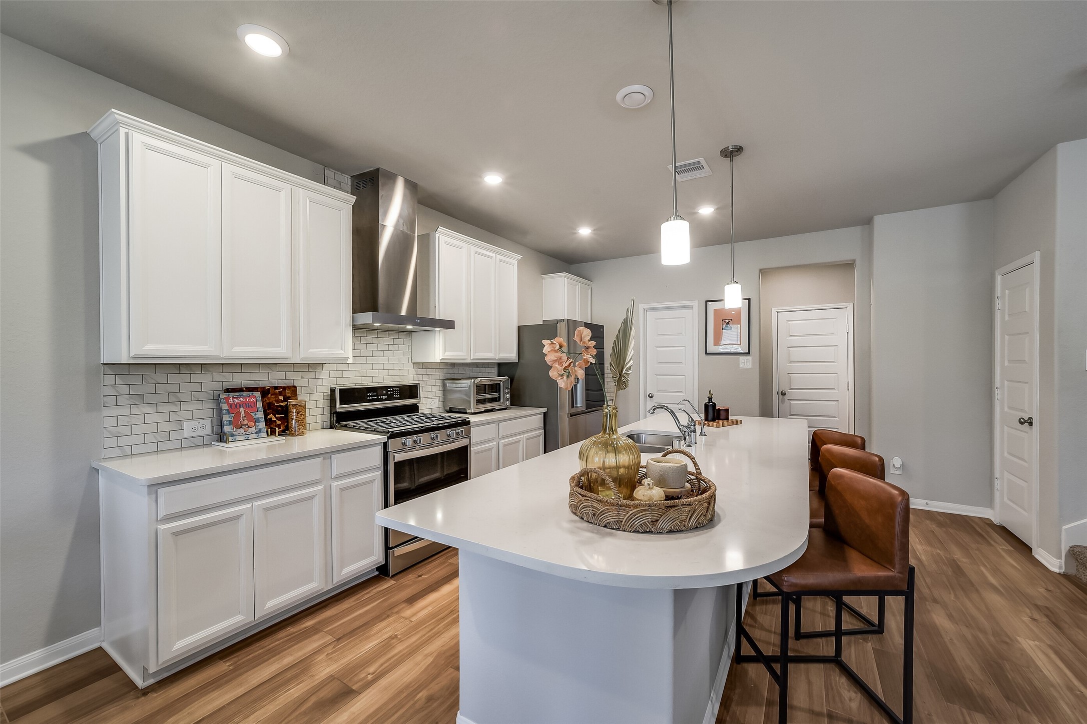 White cabinetry, light countertops, and a subway tile backsplash give the kitchen a fresh, cohesive feel, with an island providing additional workspace and seating. White cabinetry, light countertops, and a subway tile backsplash give the kitchen a fresh, cohesive feel, with an island providing additional workspace and seating.