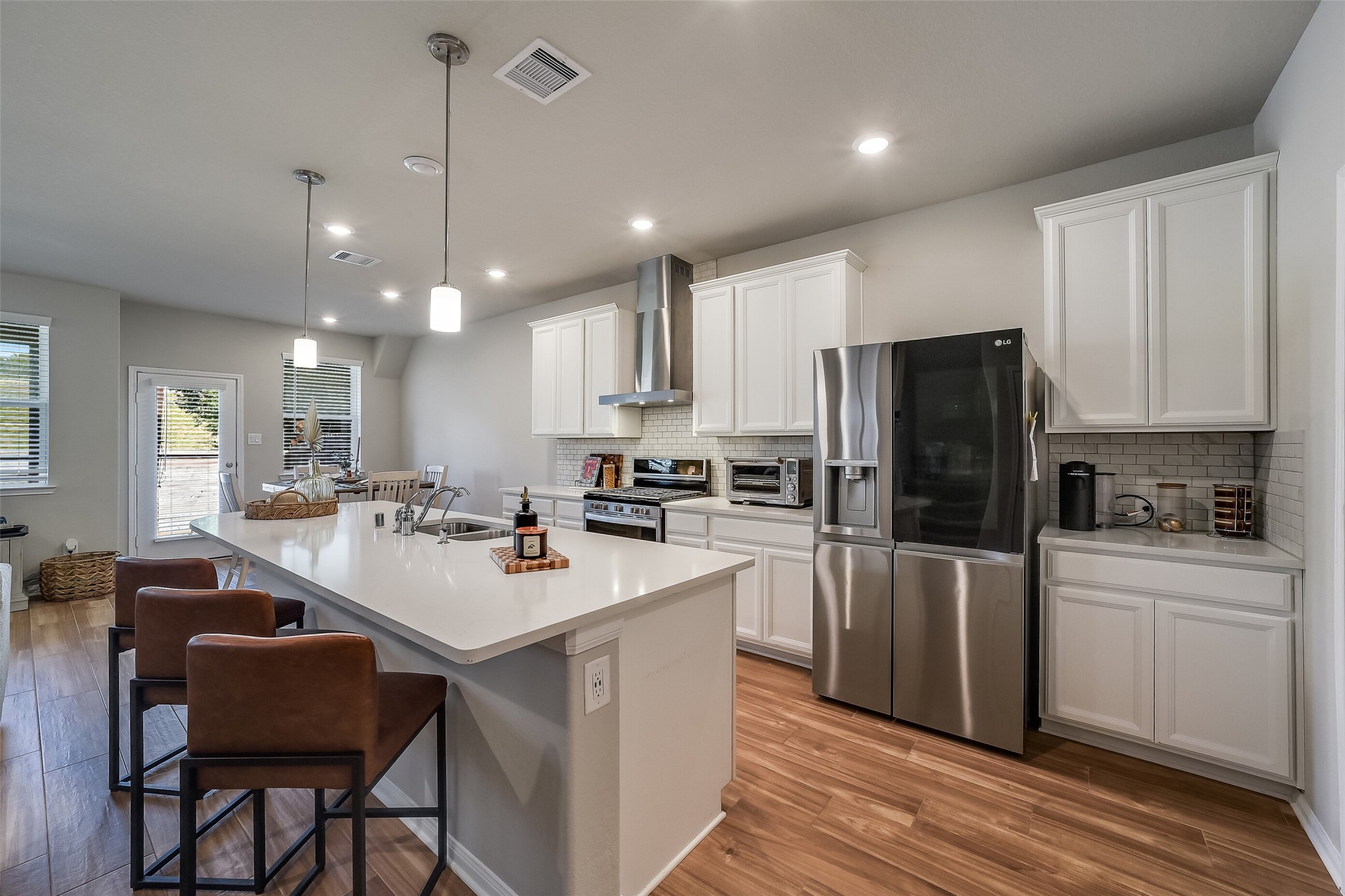 Stainless steel appliances pair with white cabinetry and light countertops, while the curved island creates a comfortable gathering place.