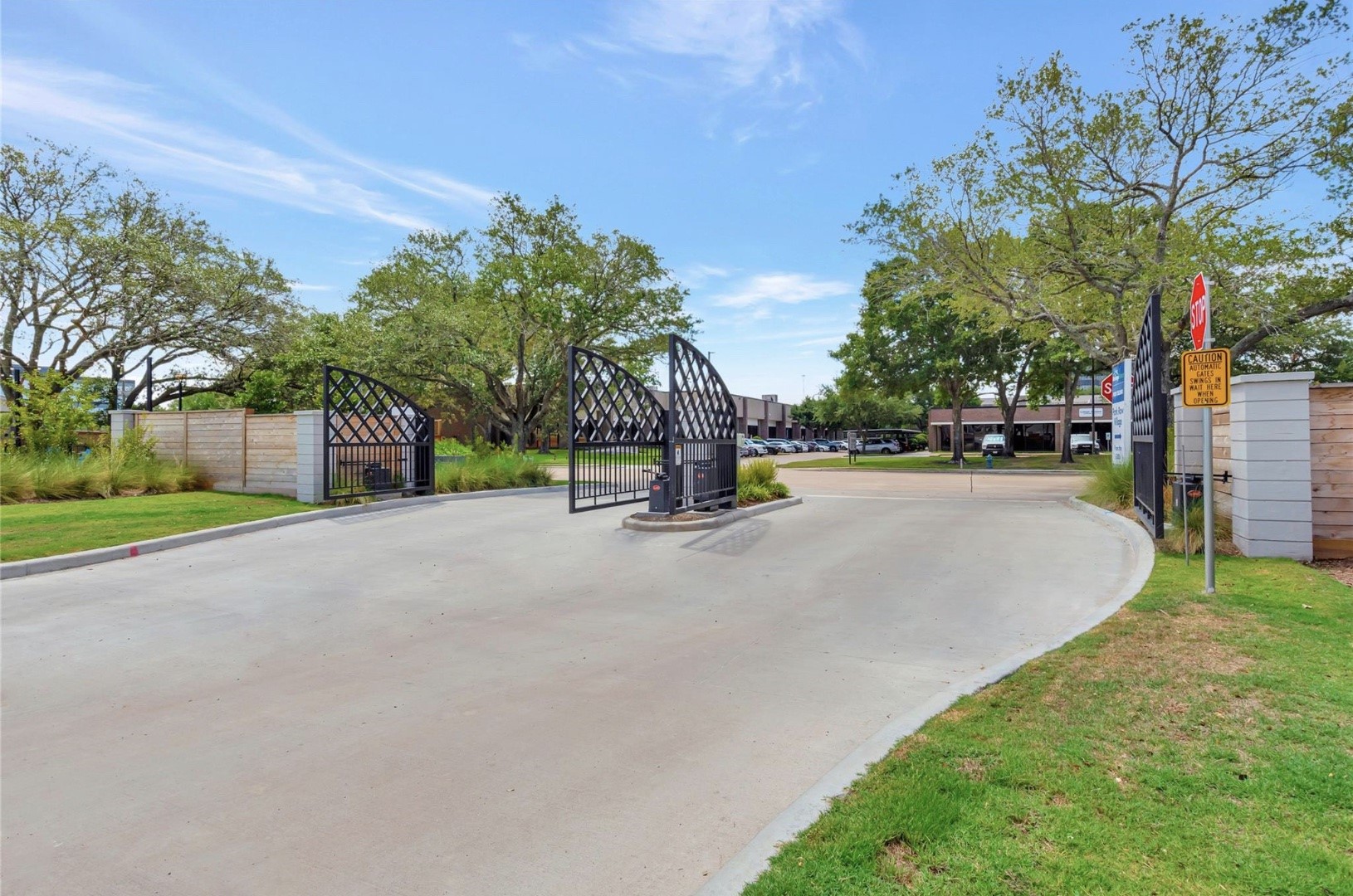 The gated vehicle entrance welcomes you into Park Row Village, with landscaped surroundings lining the approach.