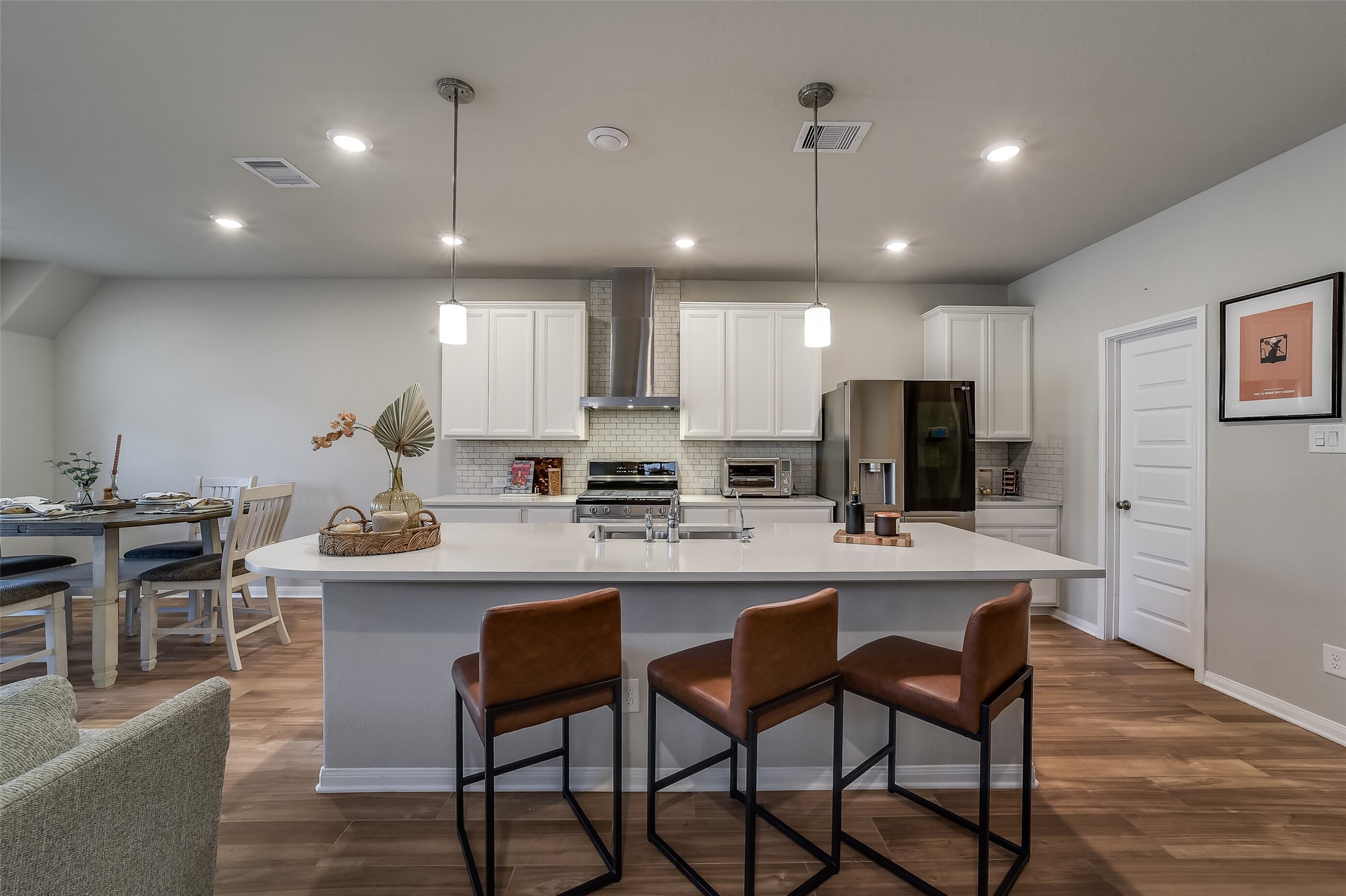 Pull up a seat for morning coffee or conversation at the generous kitchen island, complemented by pendant lighting and white cabinetry. Pull up a seat for morning coffee or conversation at the generous kitchen island, complemented by pendant lighting and white cabinetry.